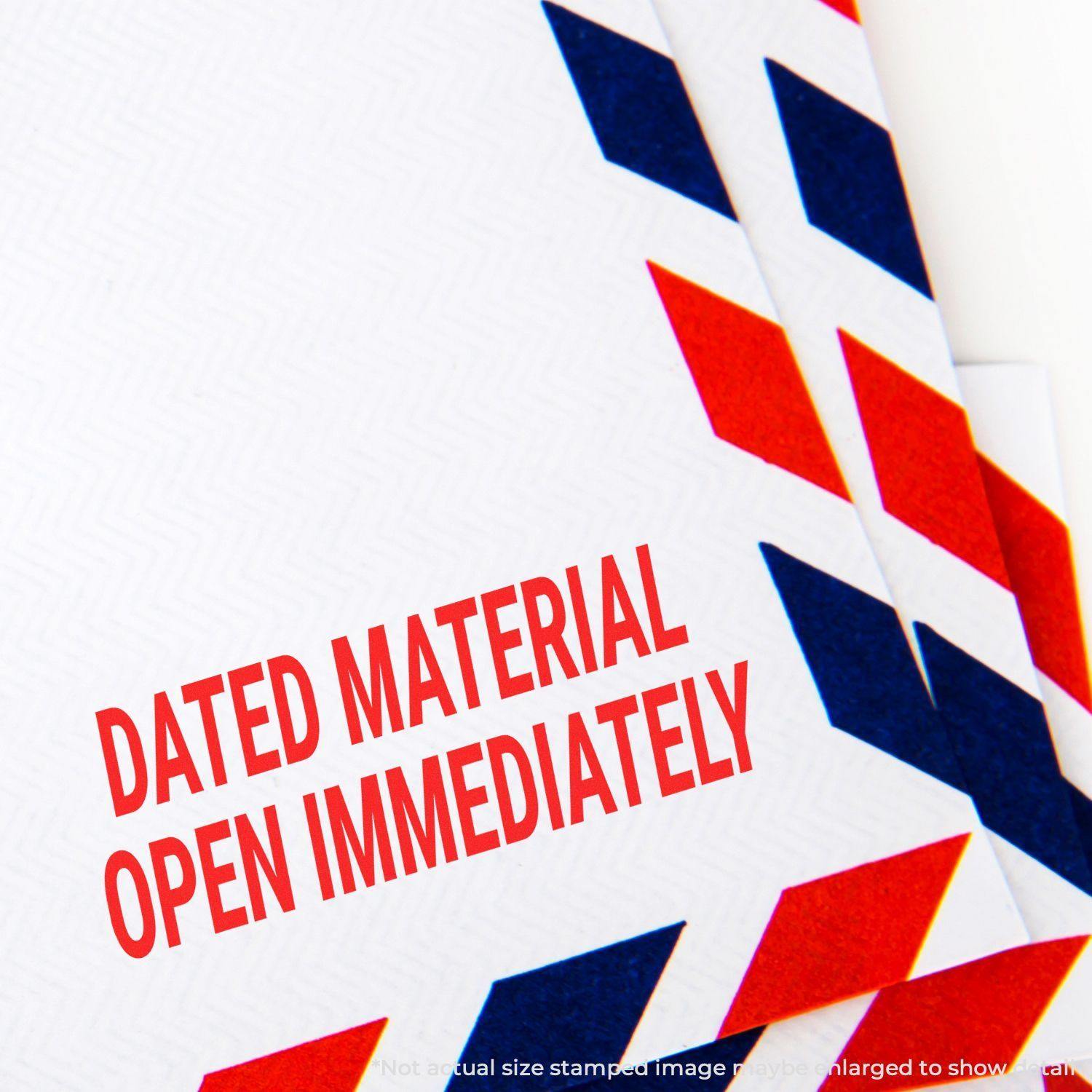 Slim Pre-Inked Dated Material Open Immediately Stamp used on a white envelope with red and blue chevron border design.