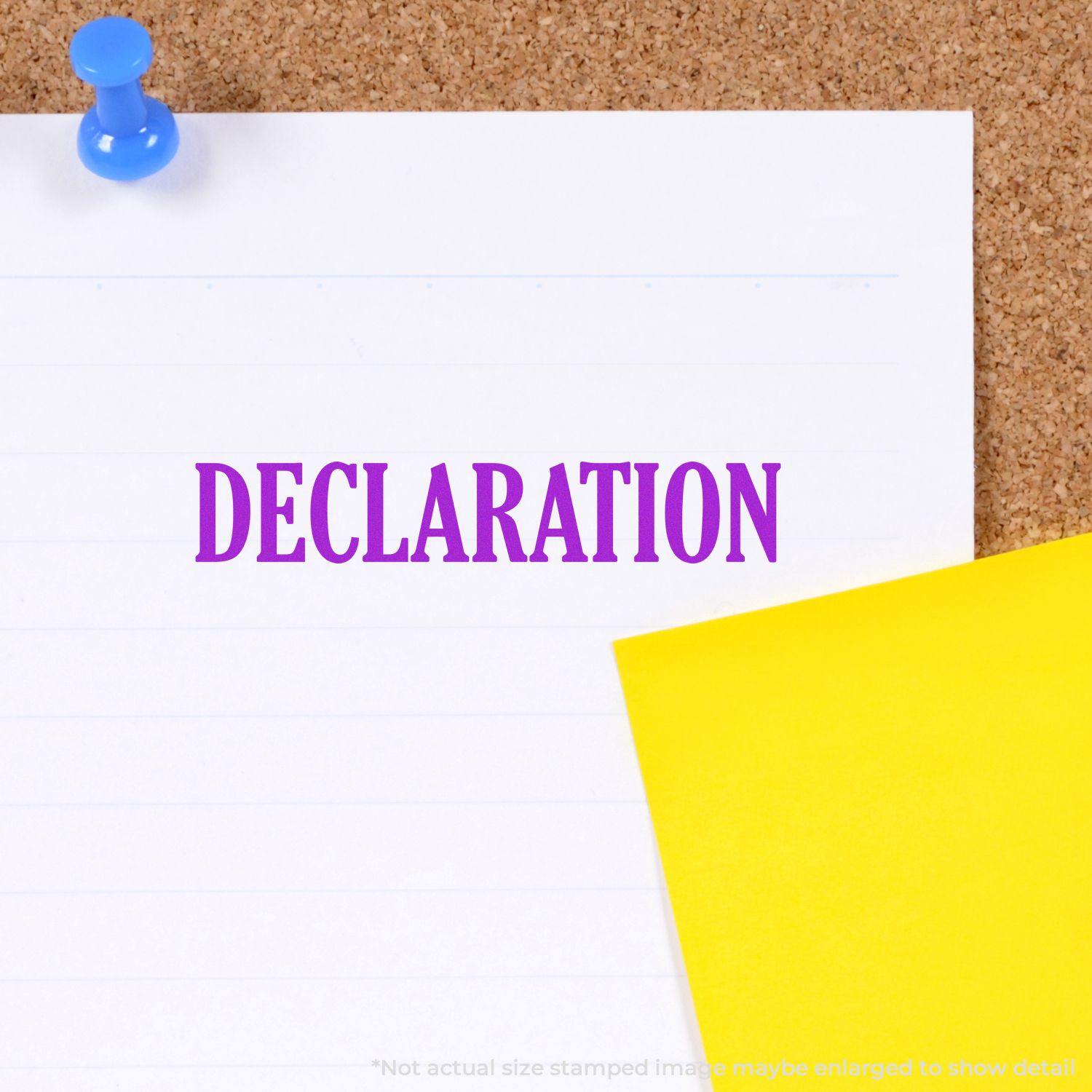 Large Self Inking Declaration Stamp used on white paper pinned to a corkboard with a blue pushpin and a yellow sticky note nearby.