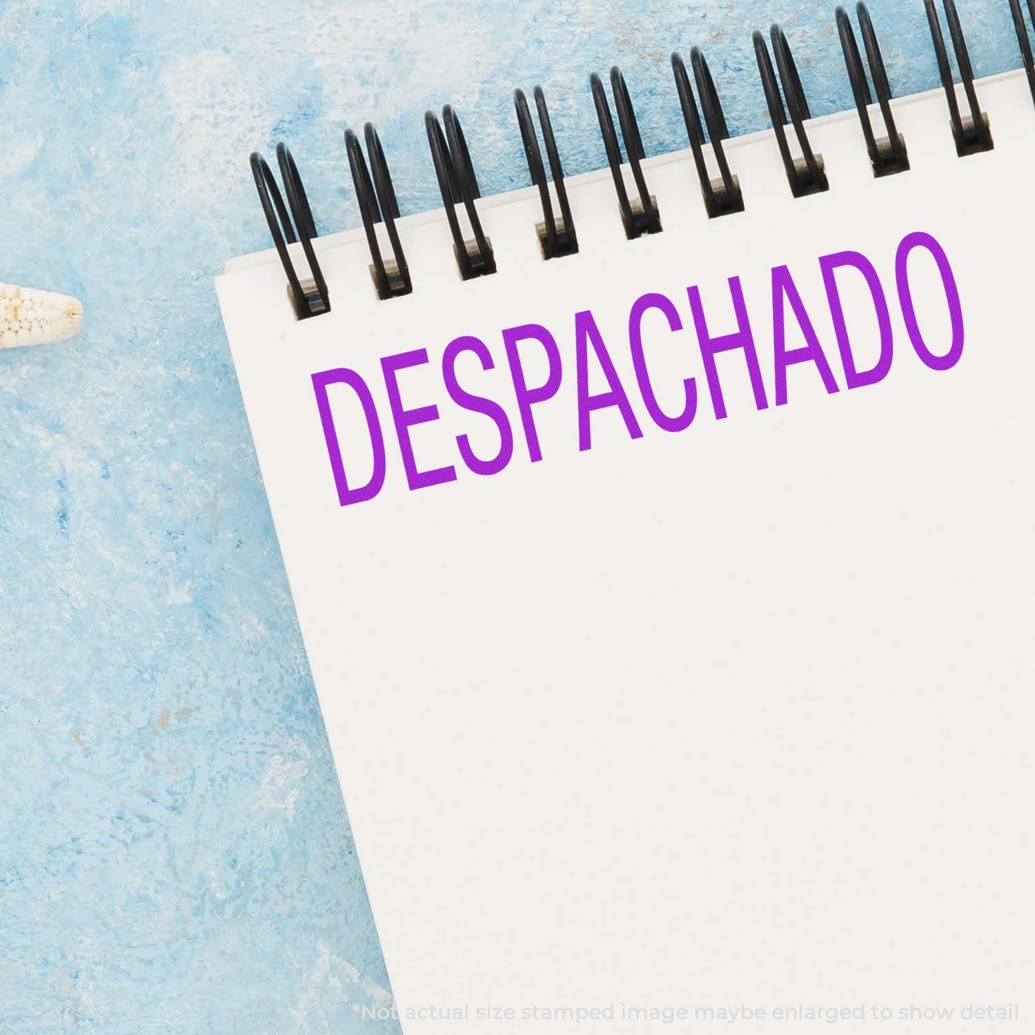 Large Pre-Inked Despachado Stamp in purple ink on a white notepad with a blue textured background.