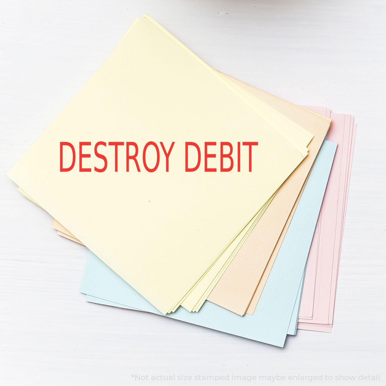 A stack of pastel-colored papers stamped with DESTROY DEBIT in red ink using the Destroy Debit Rubber Stamp.