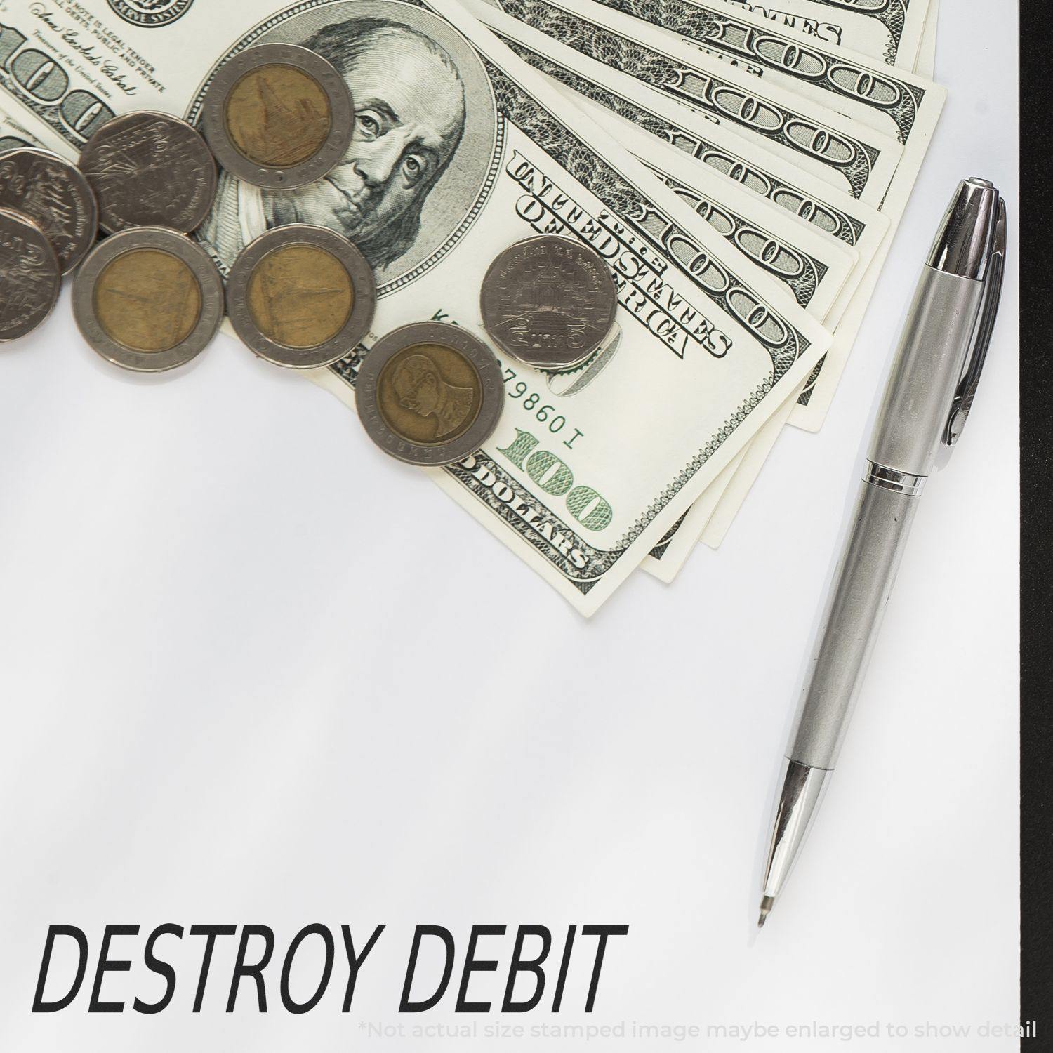 Large Self Inking Destroy Debit Stamp next to a pen, coins, and dollar bills on a white surface with DESTROY DEBIT stamped in black.