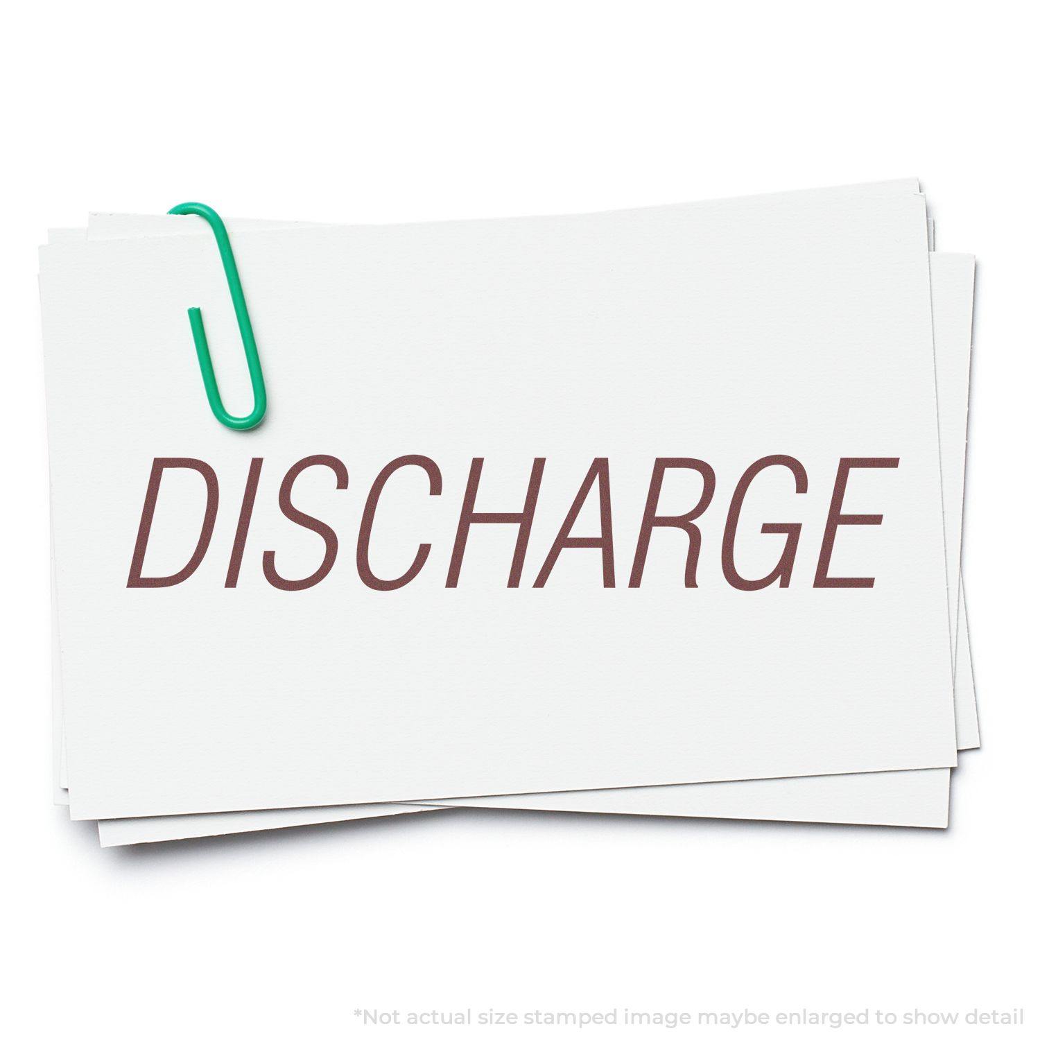 A stack of white cards with the word DISCHARGE stamped in brown ink using a Self Inking Discharge Stamp, held together by a green paperclip.