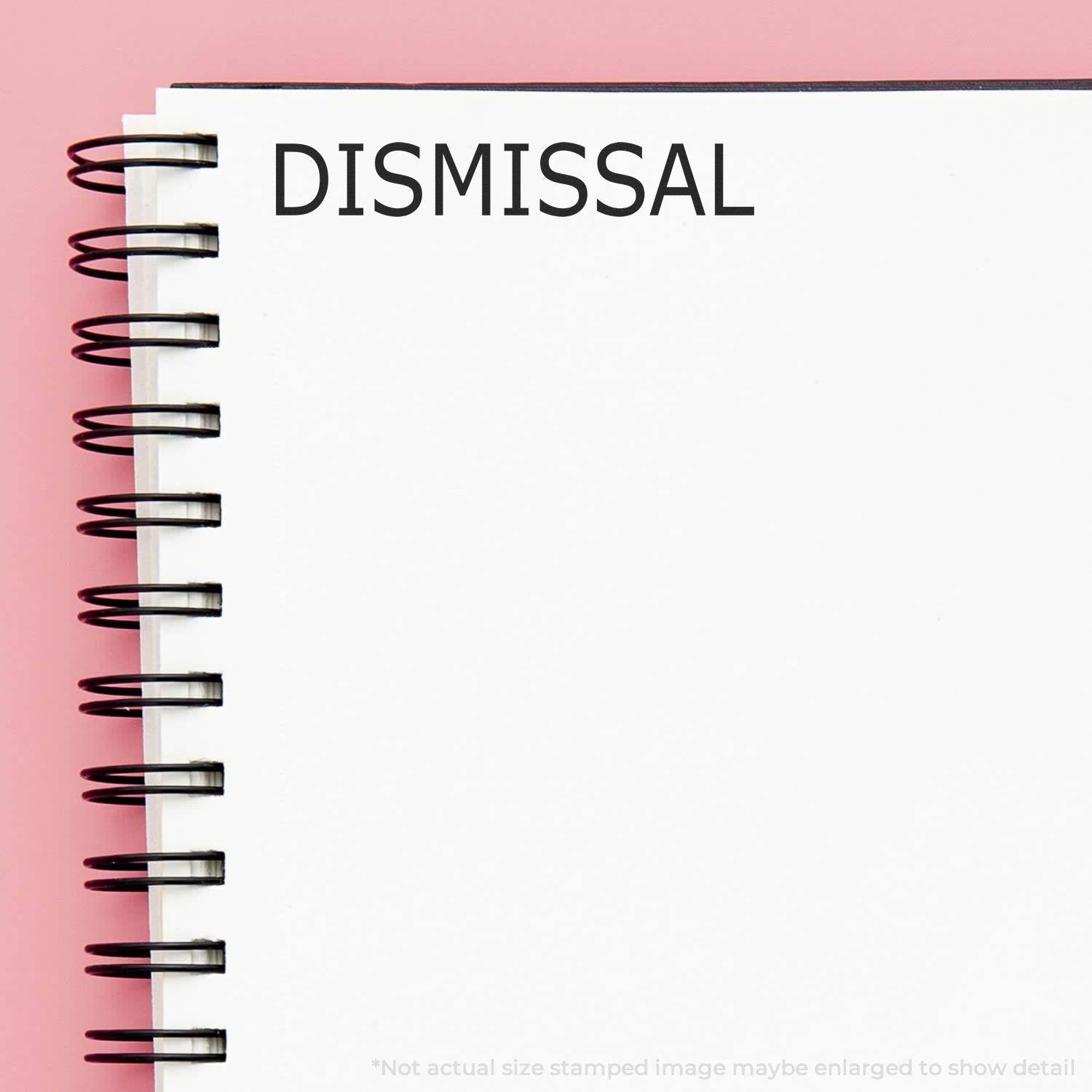 Large Dismissal Rubber Stamp imprint on a white spiral notebook with a pink background.