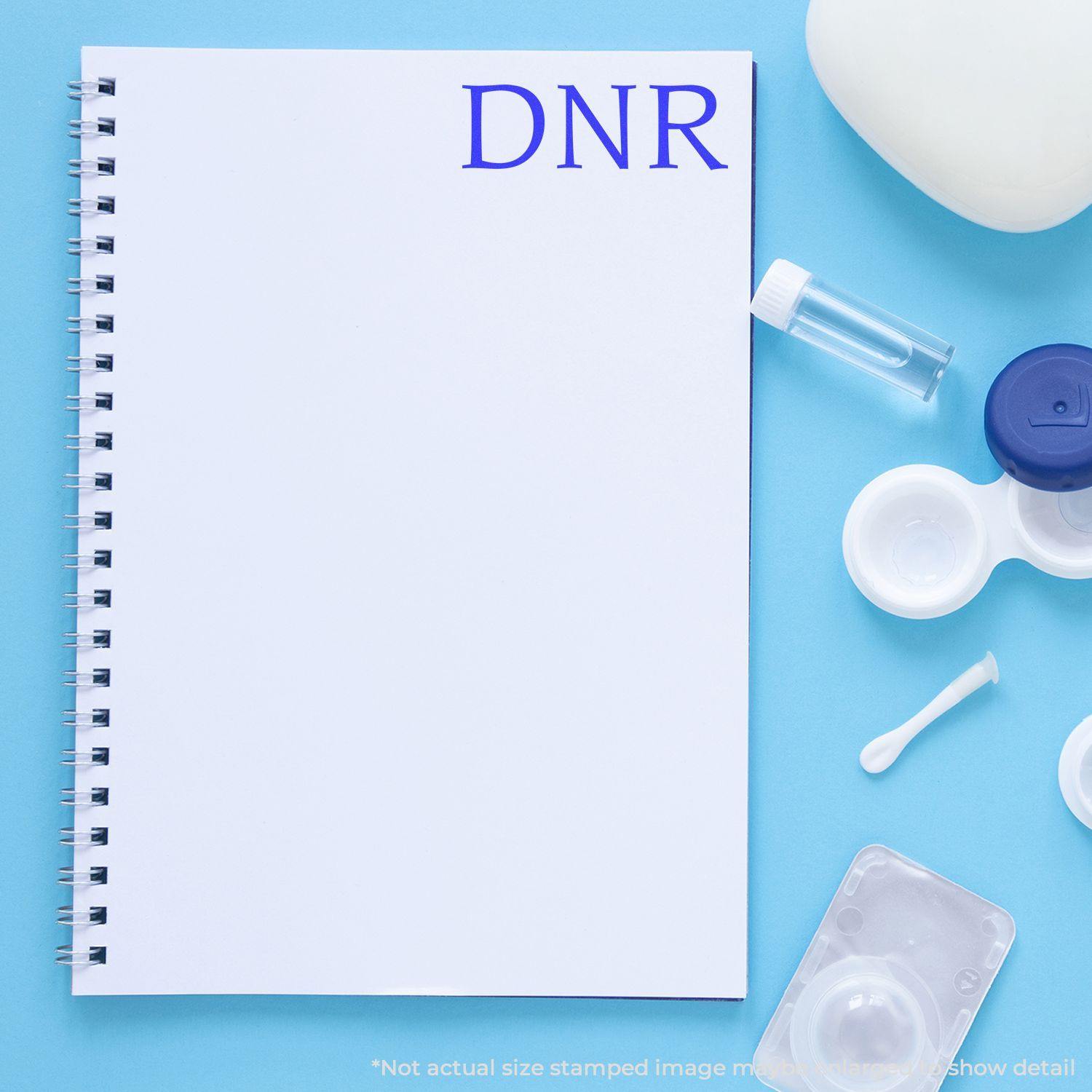 Slim Pre-Inked DNR Stamp used on a white notebook, surrounded by medical supplies on a blue background.