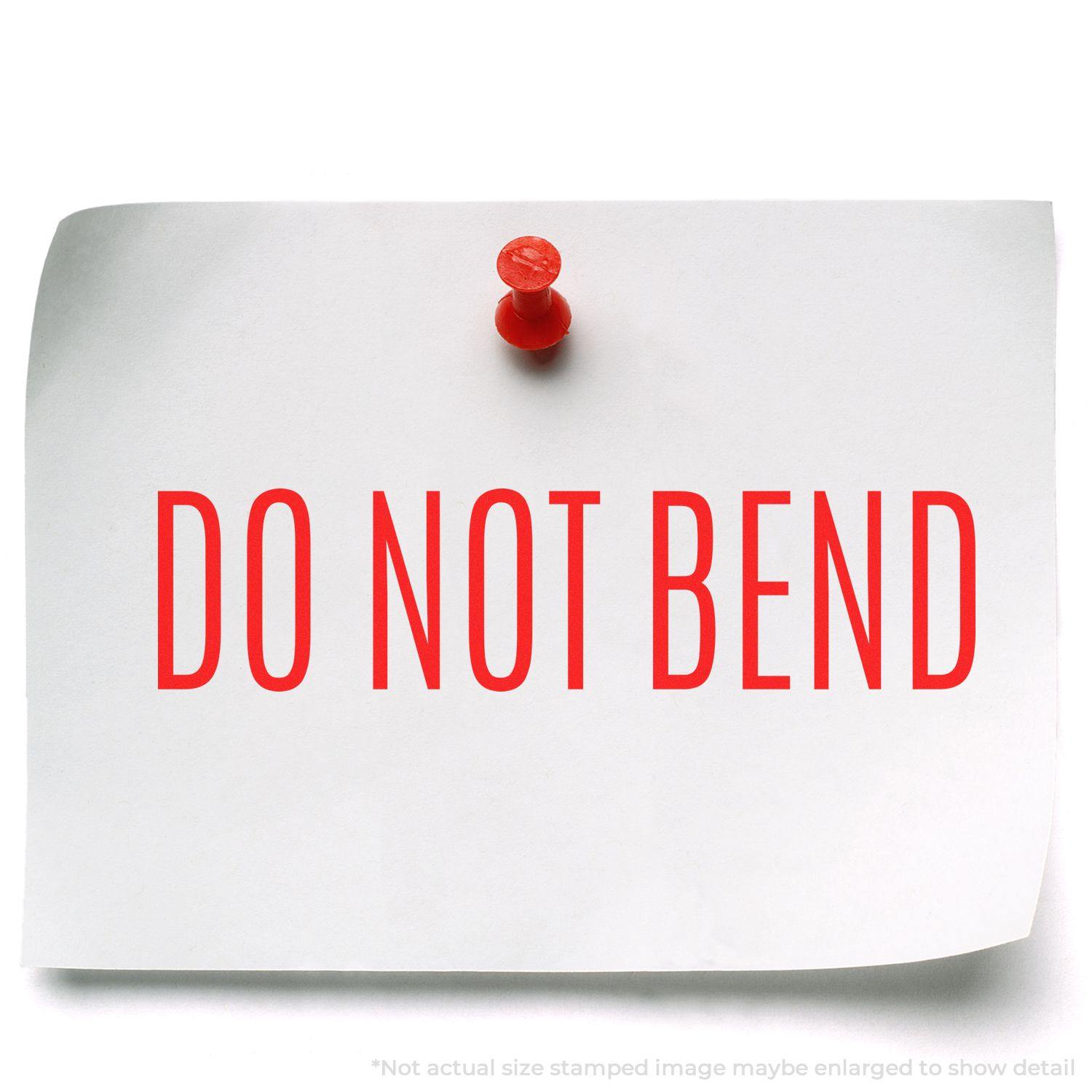 A white paper with DO NOT BEND in red, stamped using the Do Not Bend Rubber Stamp, pinned to a surface with a red pushpin.