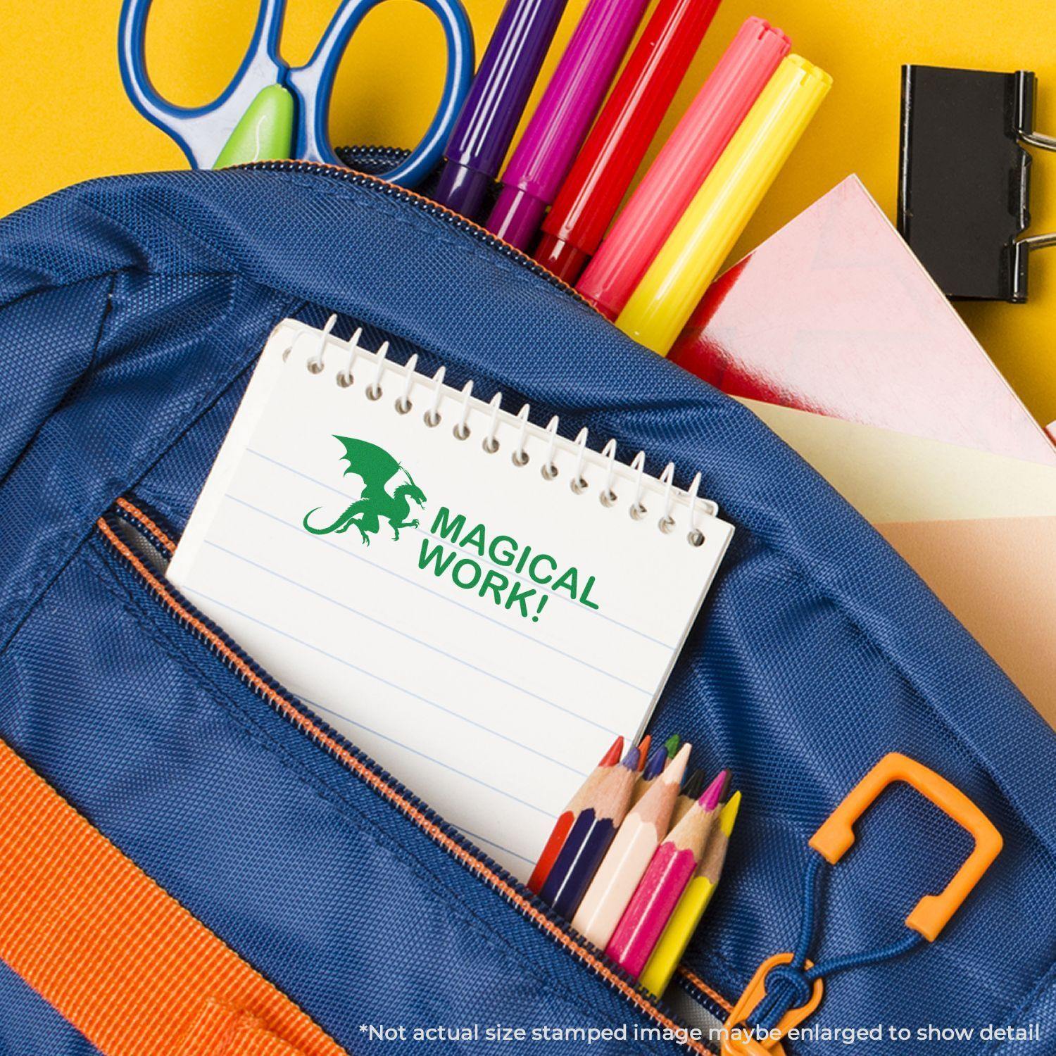 A Large Self Inking Dragon Magical Work Stamp imprint on a notepad, surrounded by colorful school supplies in a blue backpack.