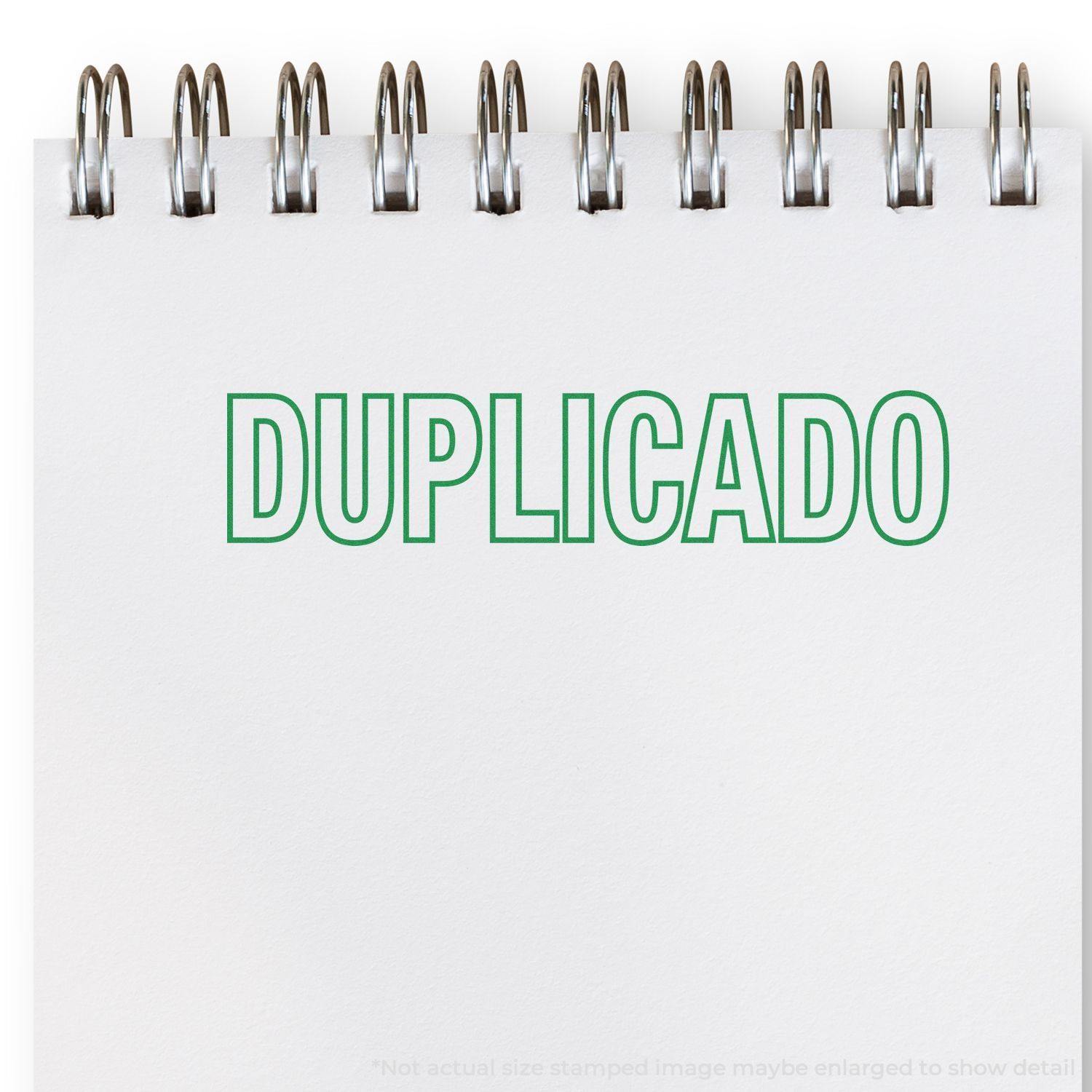 A self-inking stamp with a stamped image showing how the text "DUPLICADO" in a large outline style is displayed by it after stamping.