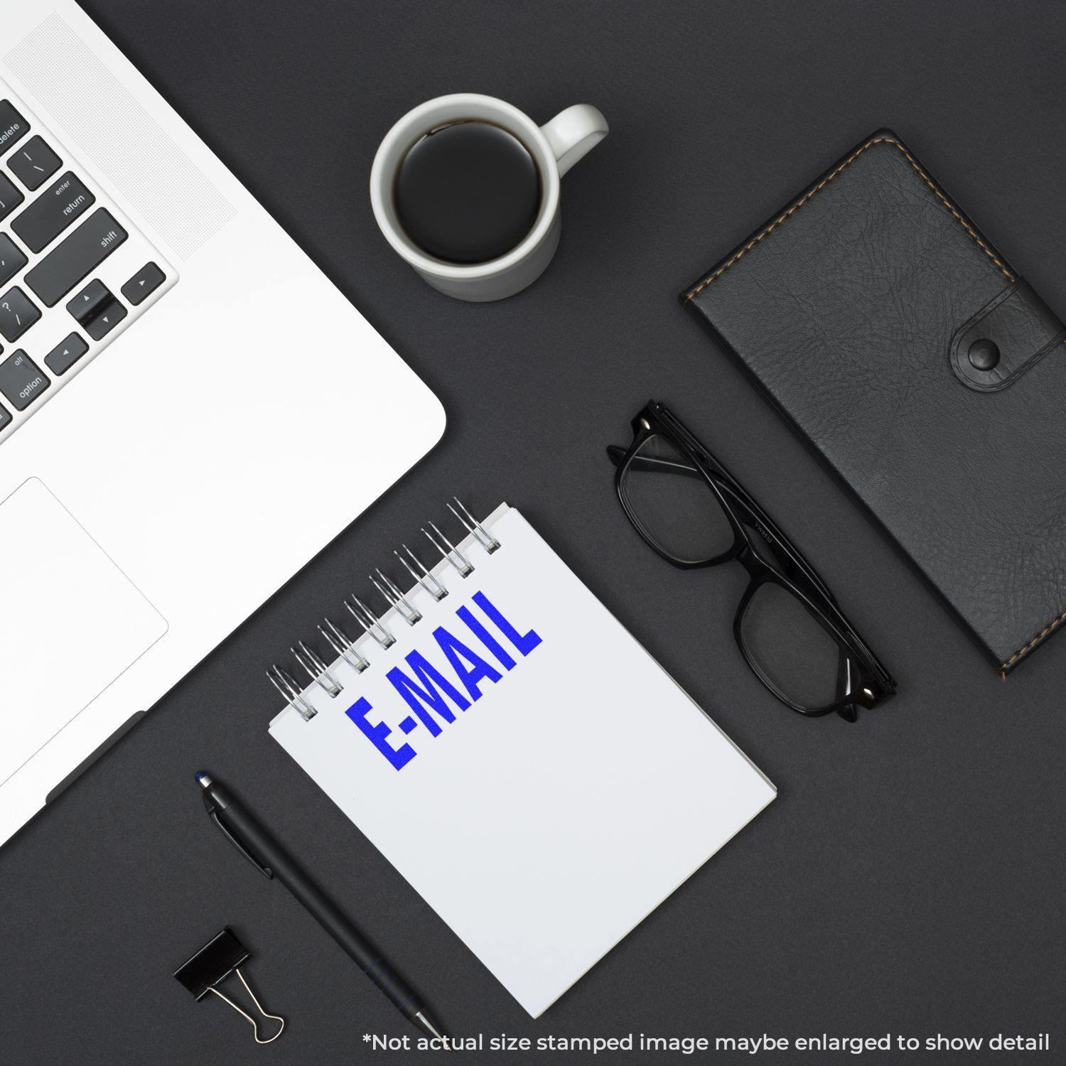 Slim Pre-Inked E-Mail Stamp used on a notepad, placed on a desk with a laptop, coffee cup, glasses, and a wallet.