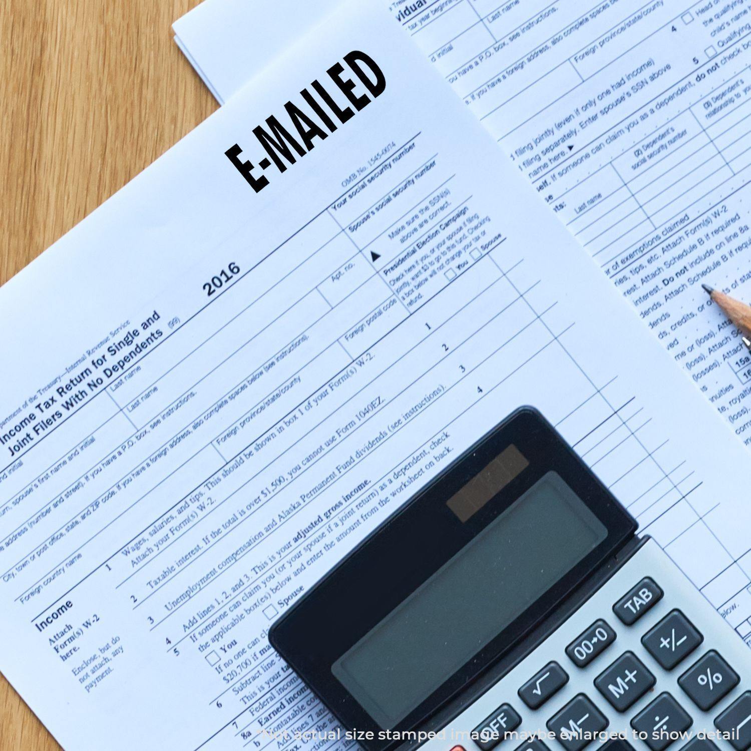 A document stamped with E-MAILED using the E Mailed Rubber Stamp, placed next to a calculator and pencil on a wooden surface.