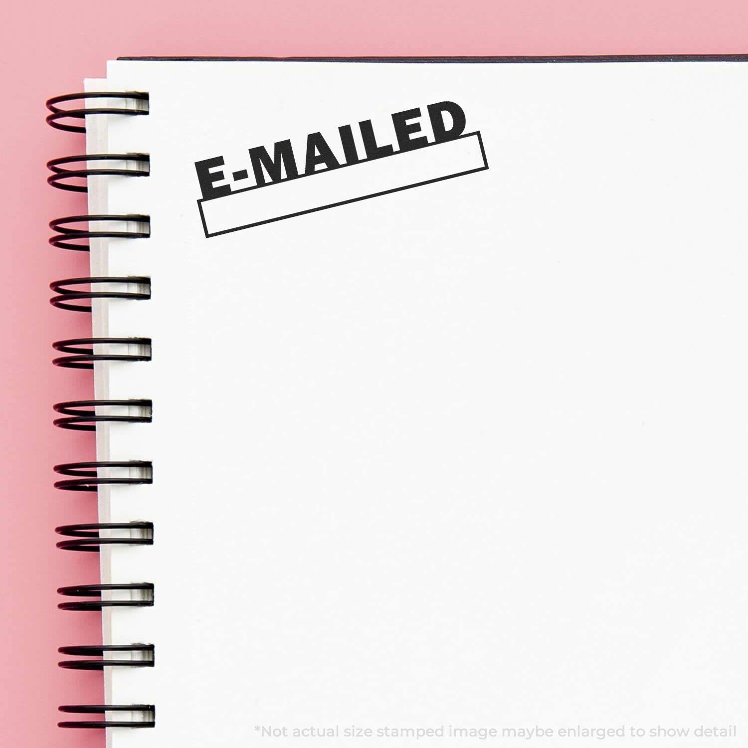 Slim Pre-Inked E-mailed with Date Box Stamp on a spiral notebook page with a pink background.