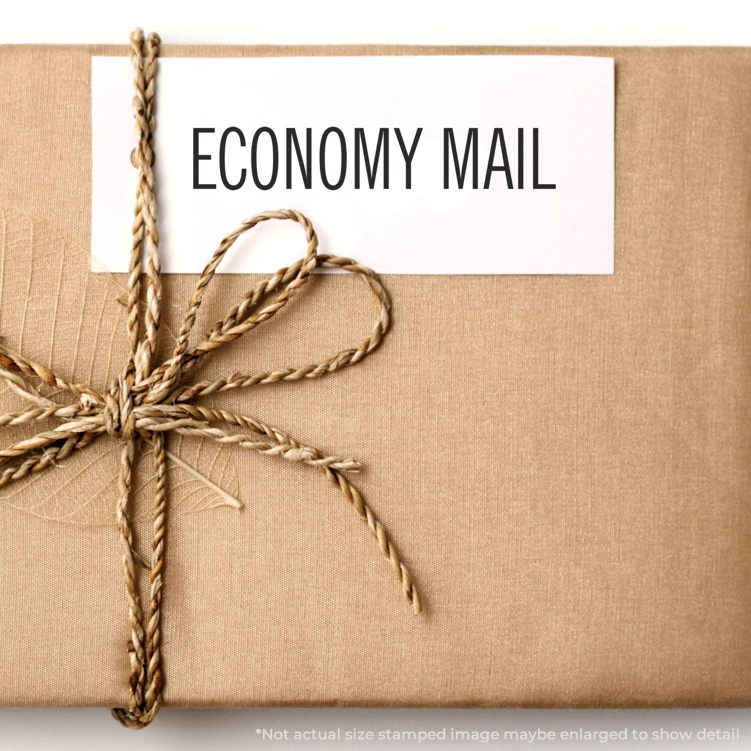 A brown package tied with twine, featuring a white label stamped with ECONOMY MAIL using the Economy Mail Rubber Stamp.