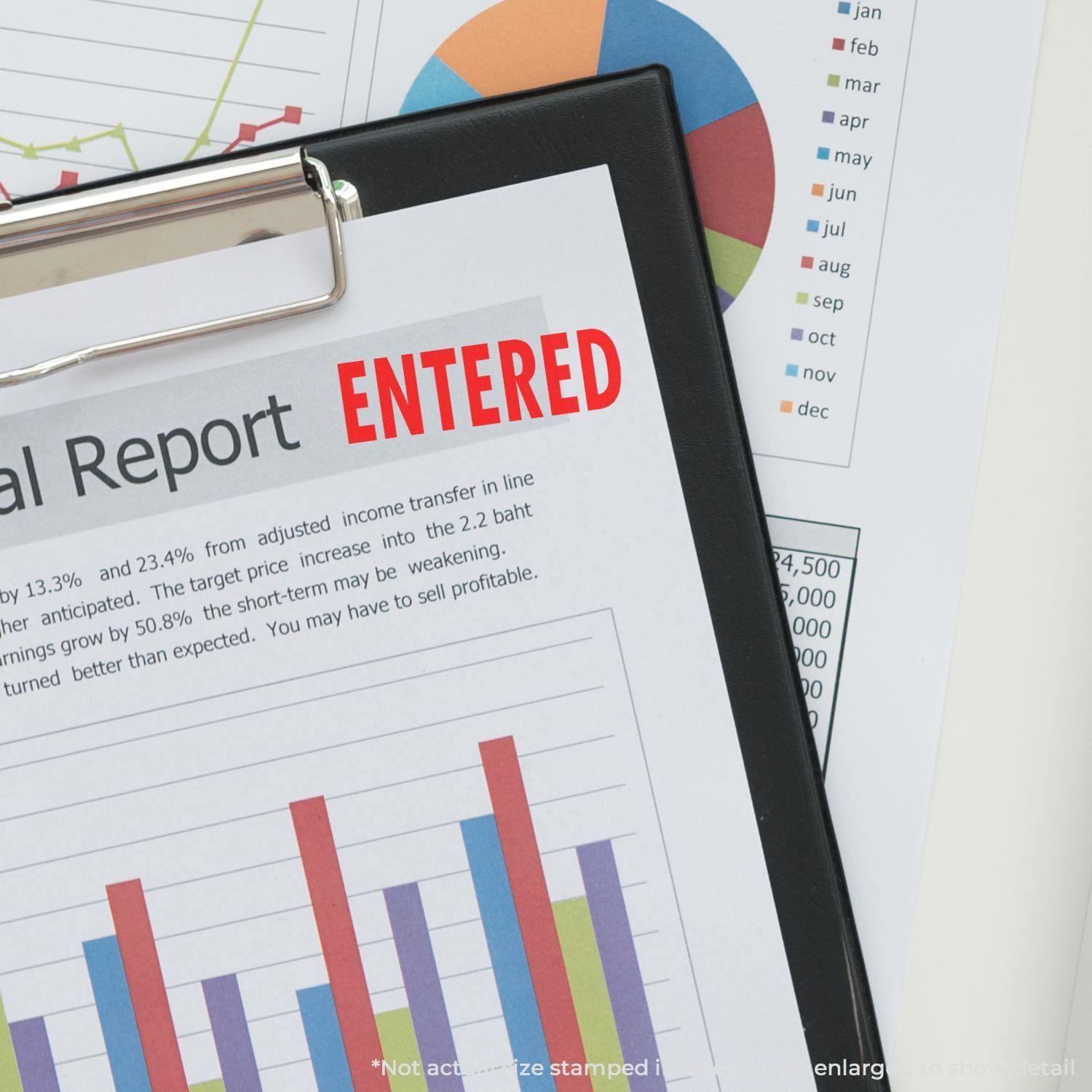 A clipboard with a financial report stamped ENTERED in red using the Entered Rubber Stamp, with charts and graphs in the background.