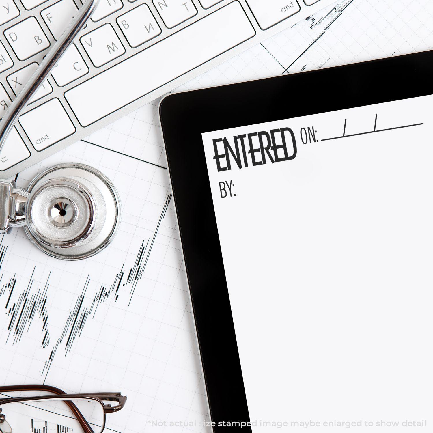 Entered On Rubber Stamp used on a document next to a stethoscope, keyboard, and graph paper on a desk.