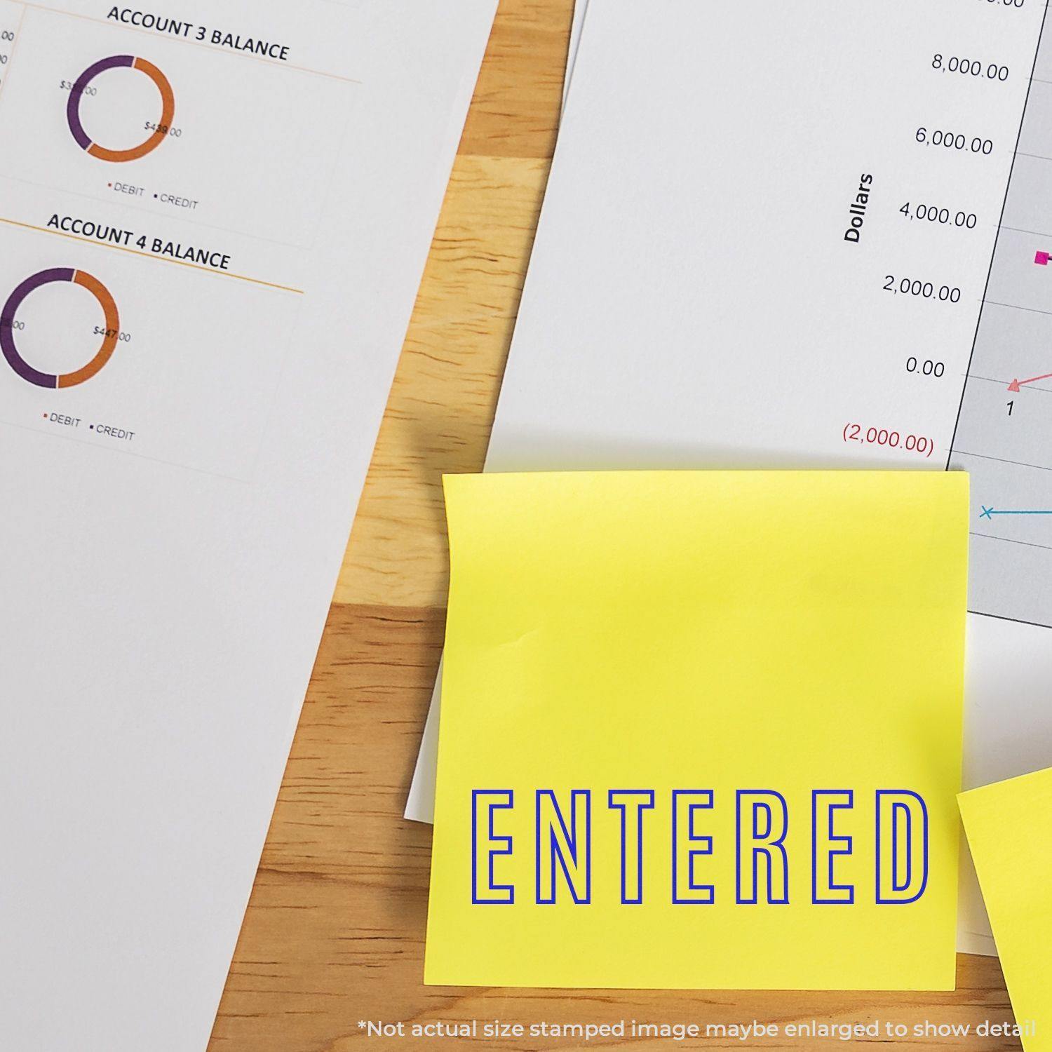 Large Self Inking Entered Outline Stamp used on a yellow sticky note, placed on a desk with financial documents and charts.