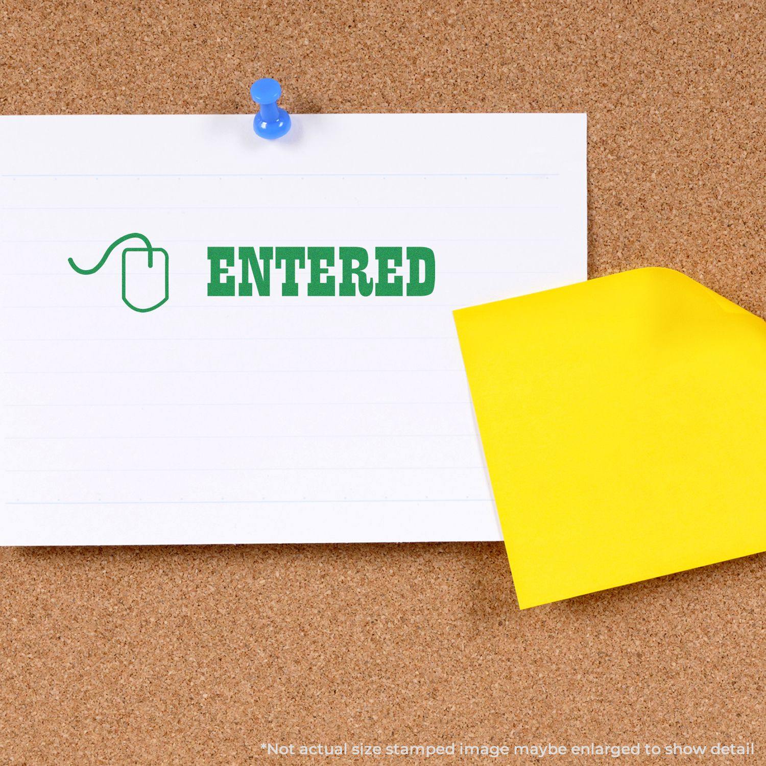 Large Self Inking Entered with Mouse Stamp in green ink on a white paper pinned to a corkboard, next to a yellow sticky note.