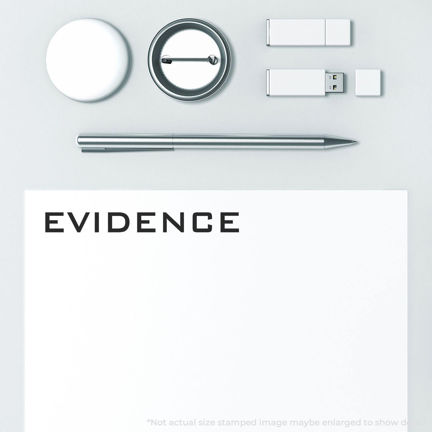 Evidence Rubber Stamp on white paper, surrounded by a pen, USB drives, a round badge, and a circular object on a light gray surface.