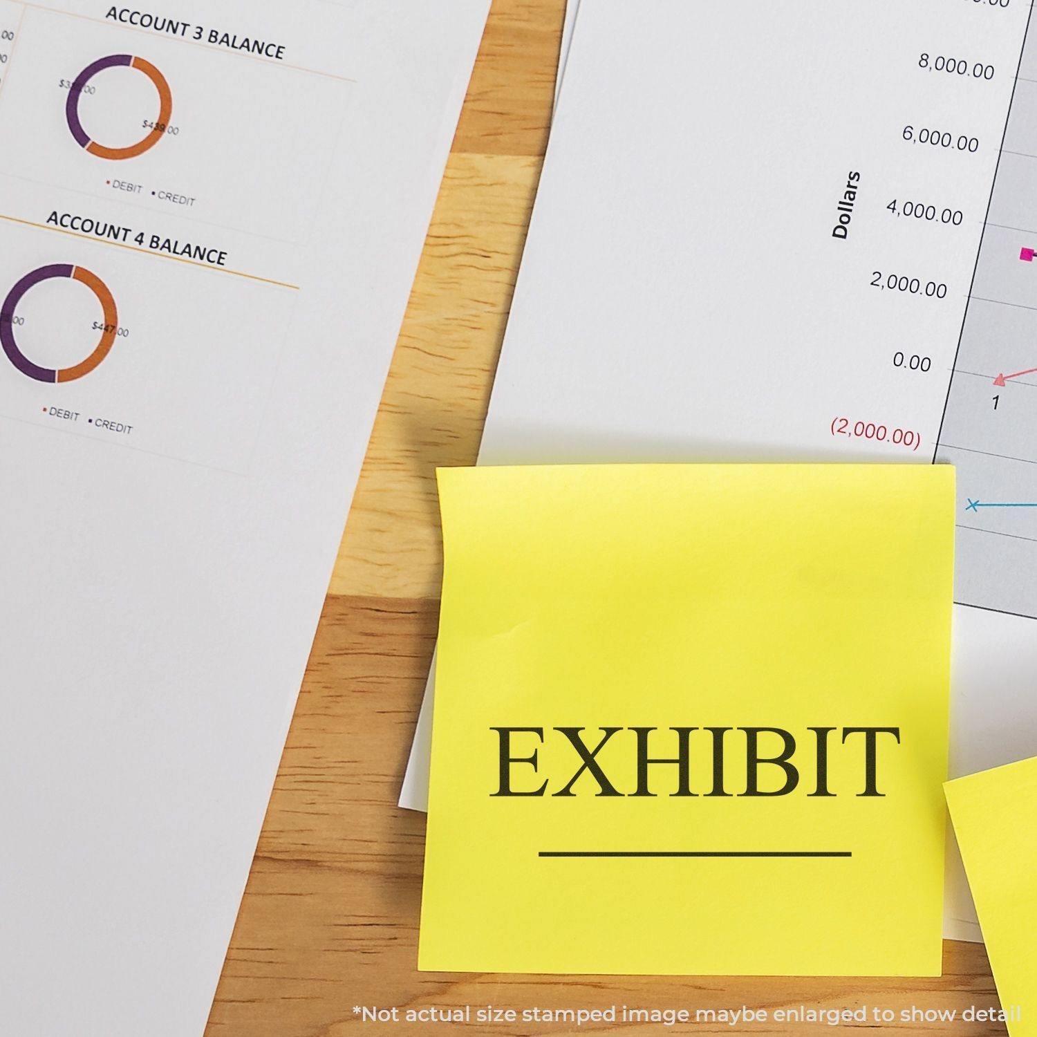 Large Pre-Inked Exhibit Stamp used on a yellow sticky note labeled EXHIBIT next to financial documents on a wooden desk.