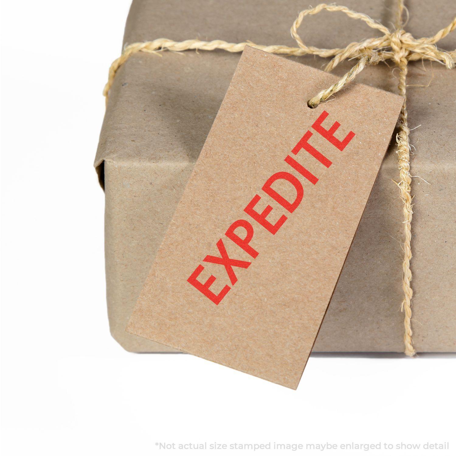 A brown package tied with twine, featuring a tag stamped with EXPEDITE in red using the Large Pre-Inked Expedite Stamp.