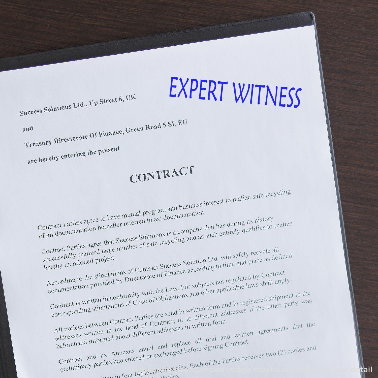 A document stamped with 'Expert Witness' using the Expert Witness Rubber Stamp, placed on a table with a contract partially visible.