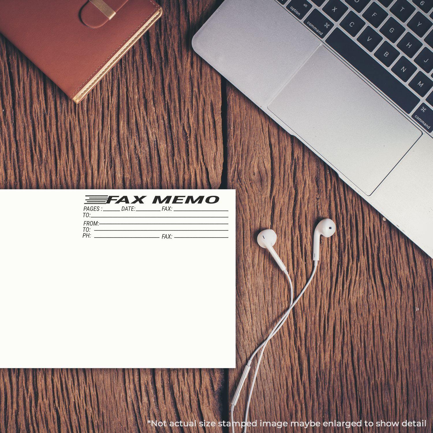 A Fax Memo Rubber Stamp is used on a fax memo sheet placed on a wooden desk next to a laptop, earphones, and a notebook.