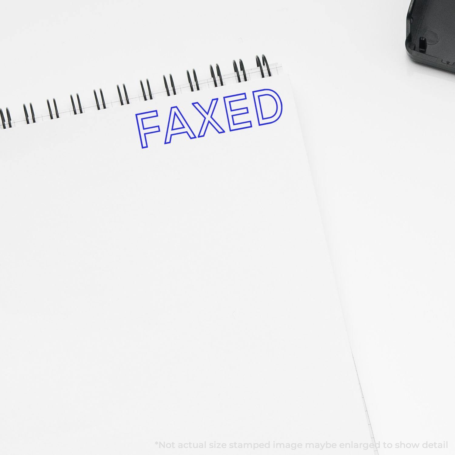 A Large Faxed Rubber Stamp imprint in blue ink on a white notepad, with the word FAXED clearly visible at the top.