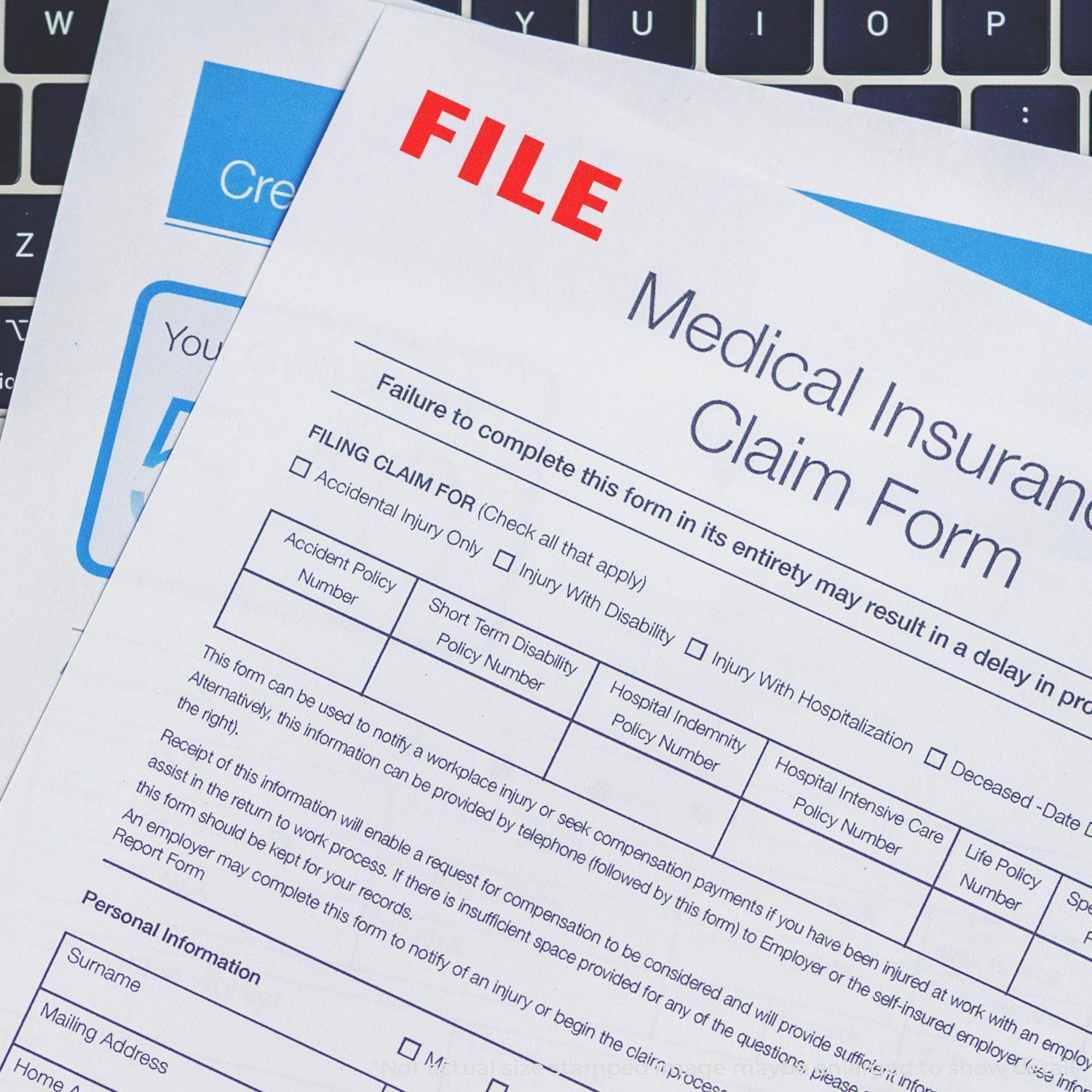 Self Inking File Stamp marking FILE in red on a medical insurance claim form, placed on a laptop keyboard.