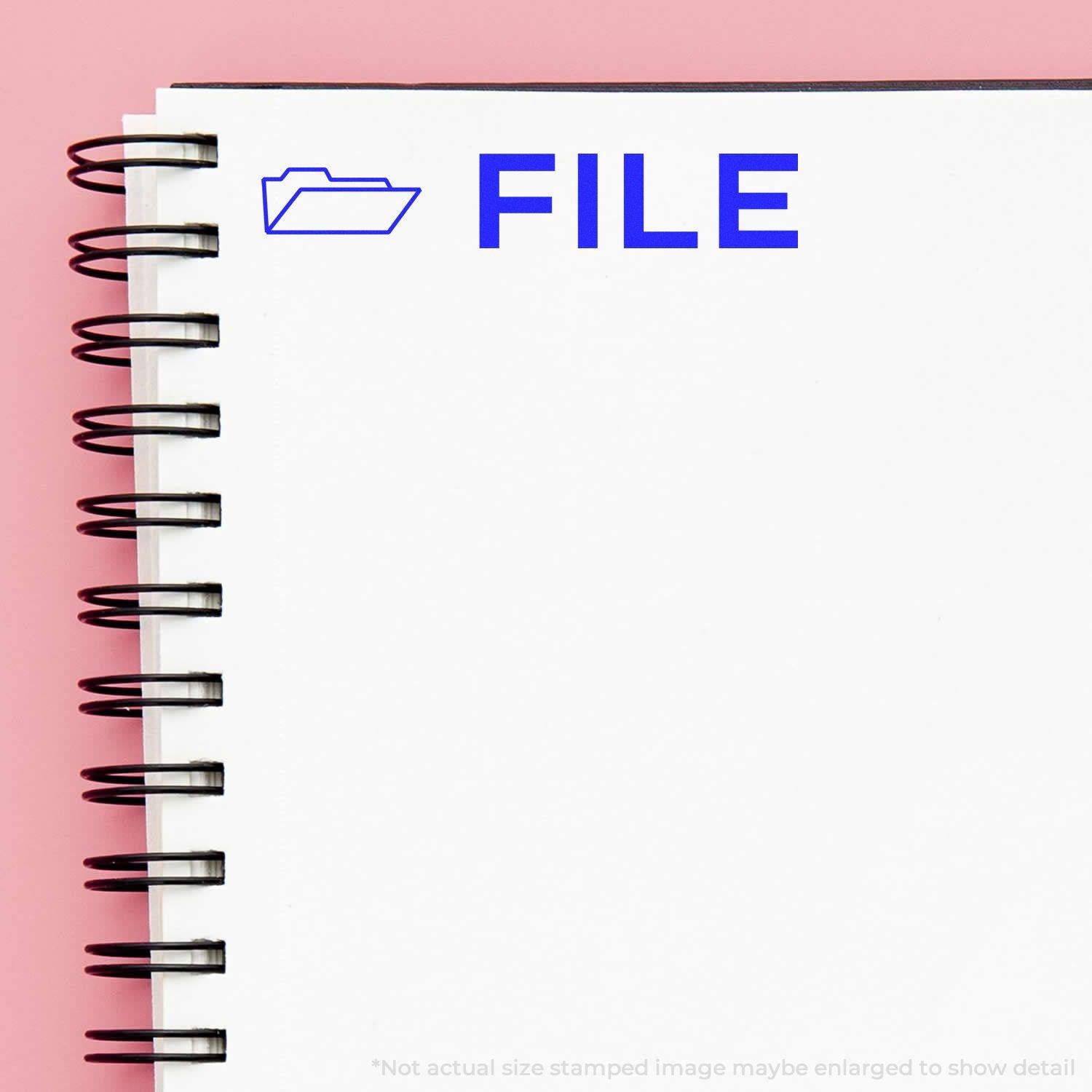 Spiral notebook with a blue FILE stamp and folder icon from the File with Folder Rubber Stamp on a pink background.