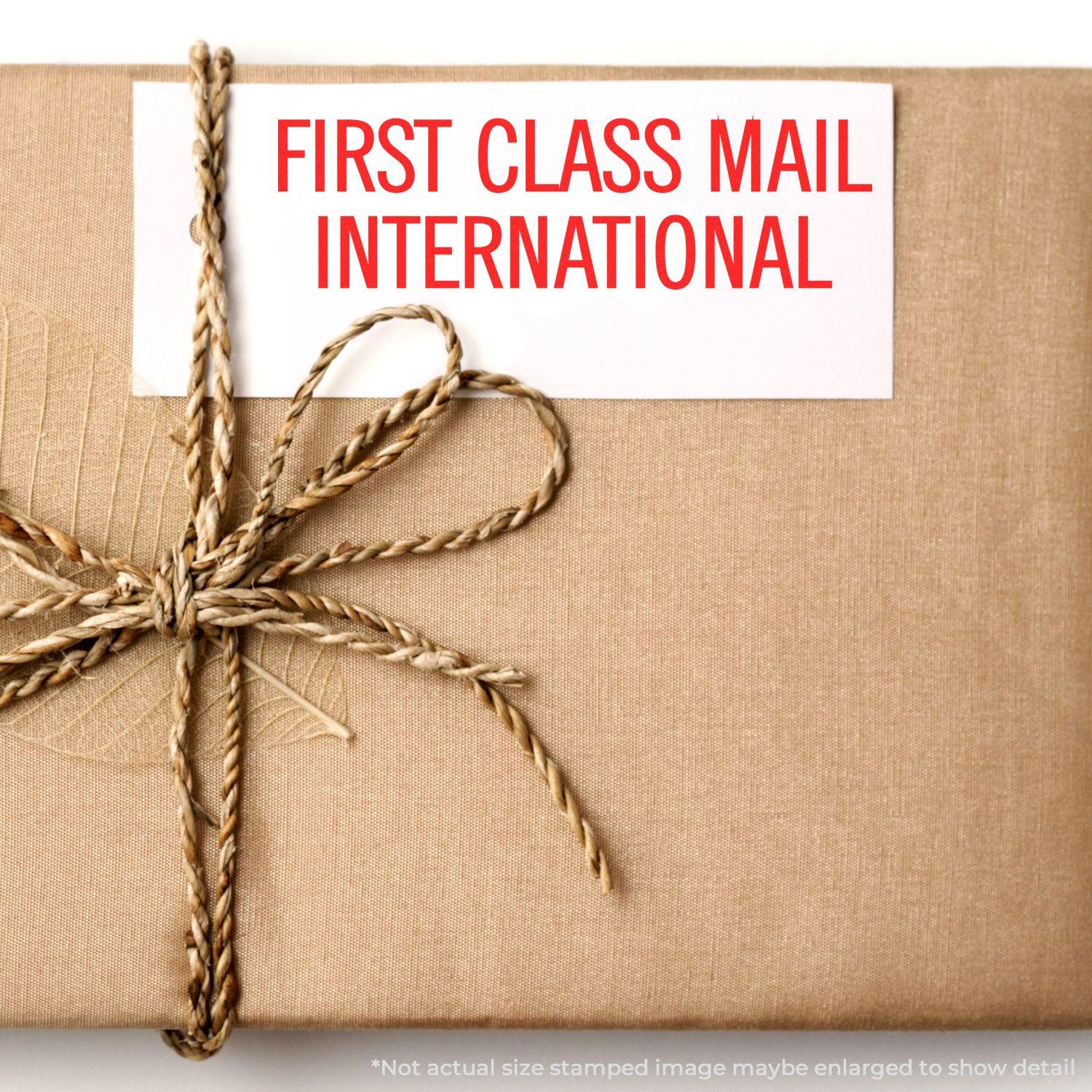 A Slim Pre-Inked First Class Mail International Stamp on a brown wrapped package tied with a twine bow.