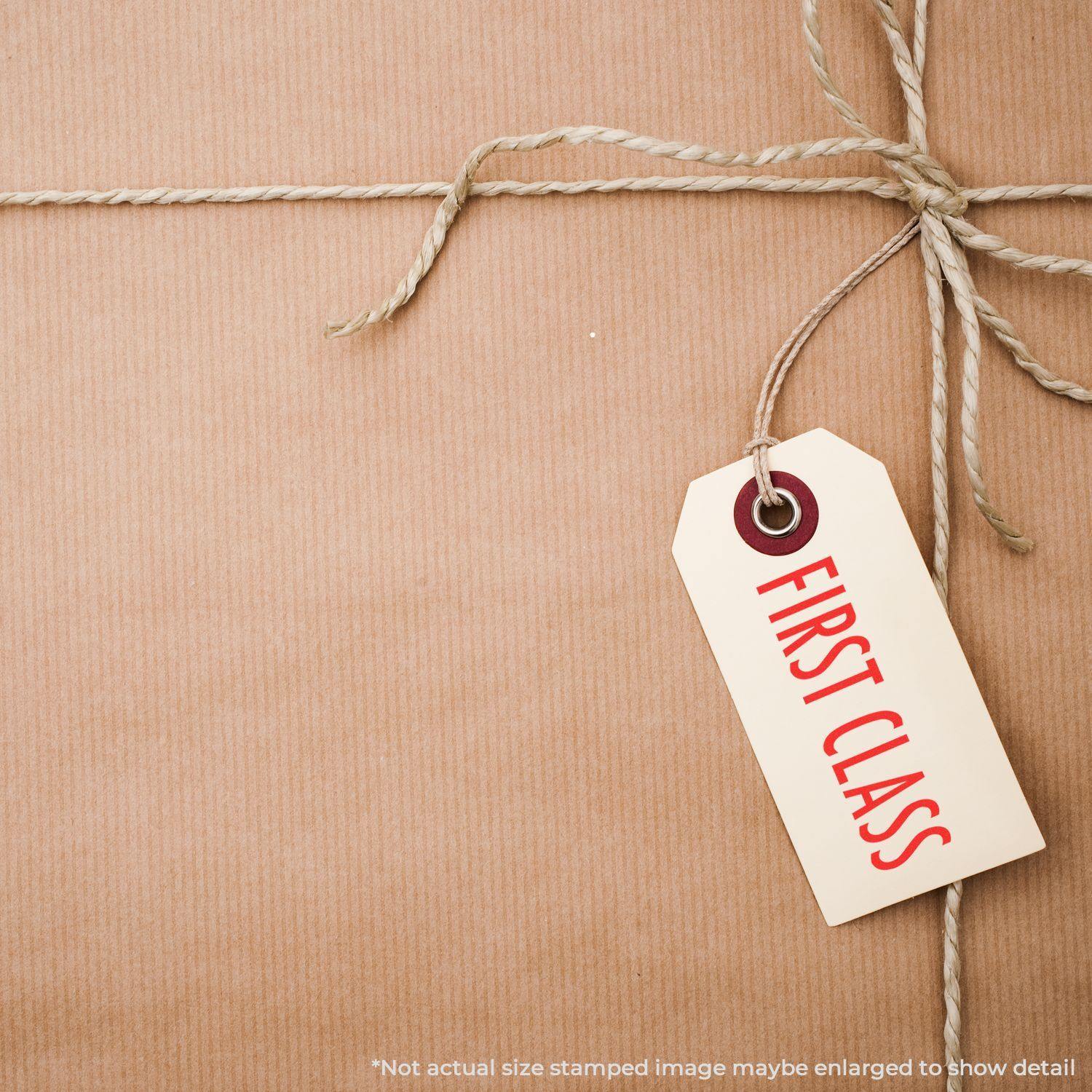 A brown package tied with twine and a tag stamped with First Class using the First Class Mailing Rubber Stamp.