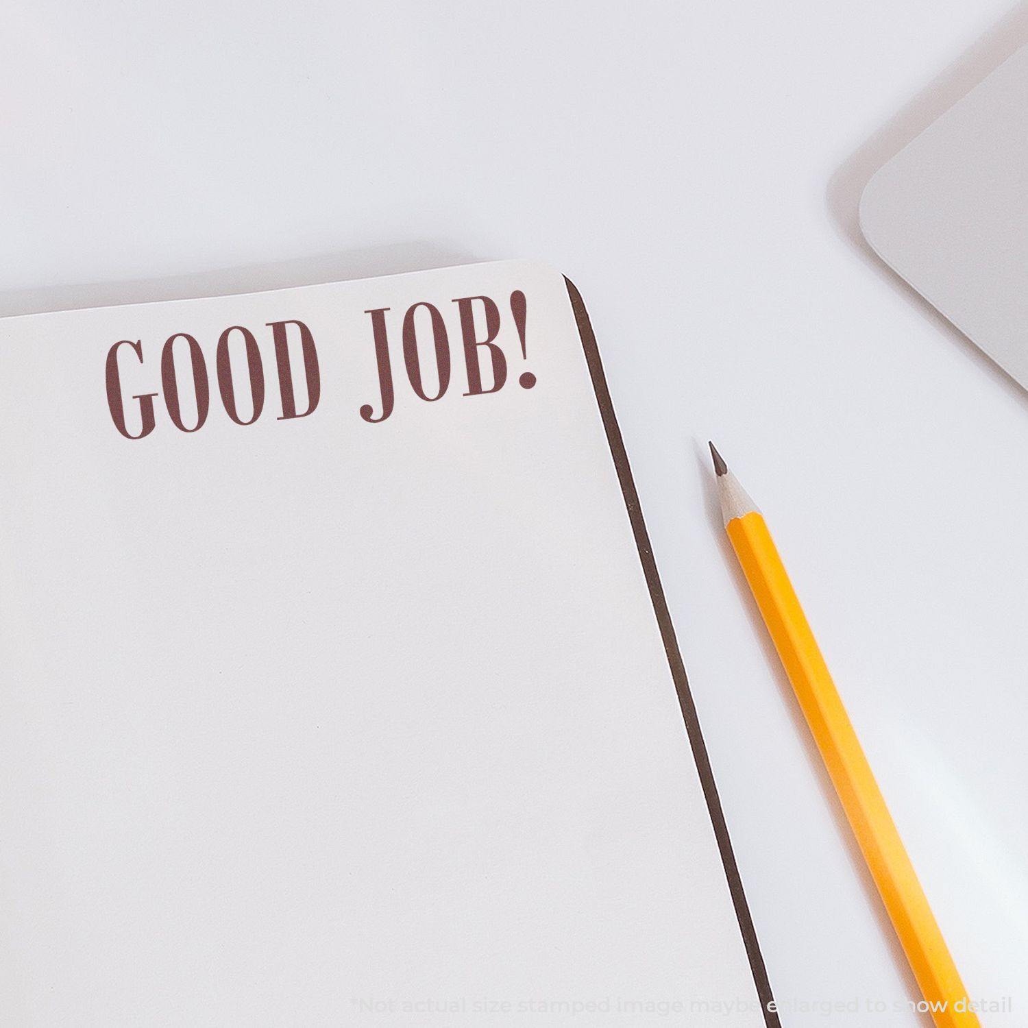 Self Inking Good Job Stamp imprint on a blank notebook page, with a yellow pencil placed beside it on a white surface.