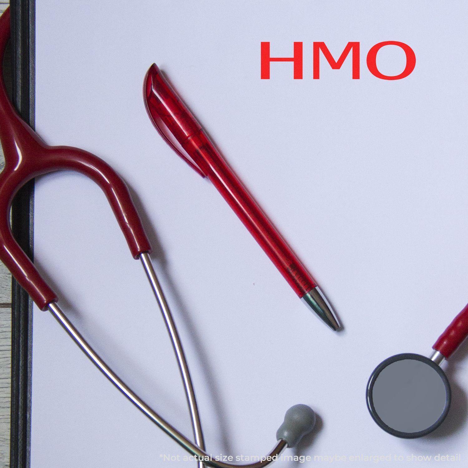 HMO Medical Rubber Stamp in use on a white clipboard with a red pen and stethoscope nearby.