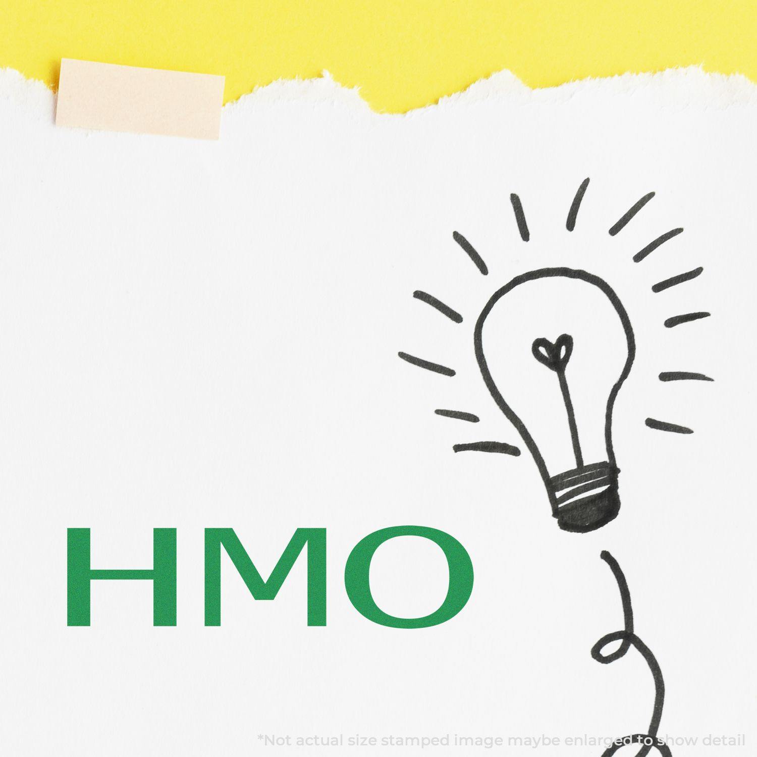 HMO Medical Rubber Stamp in use on white paper with a hand-drawn light bulb illustration and a yellow background.