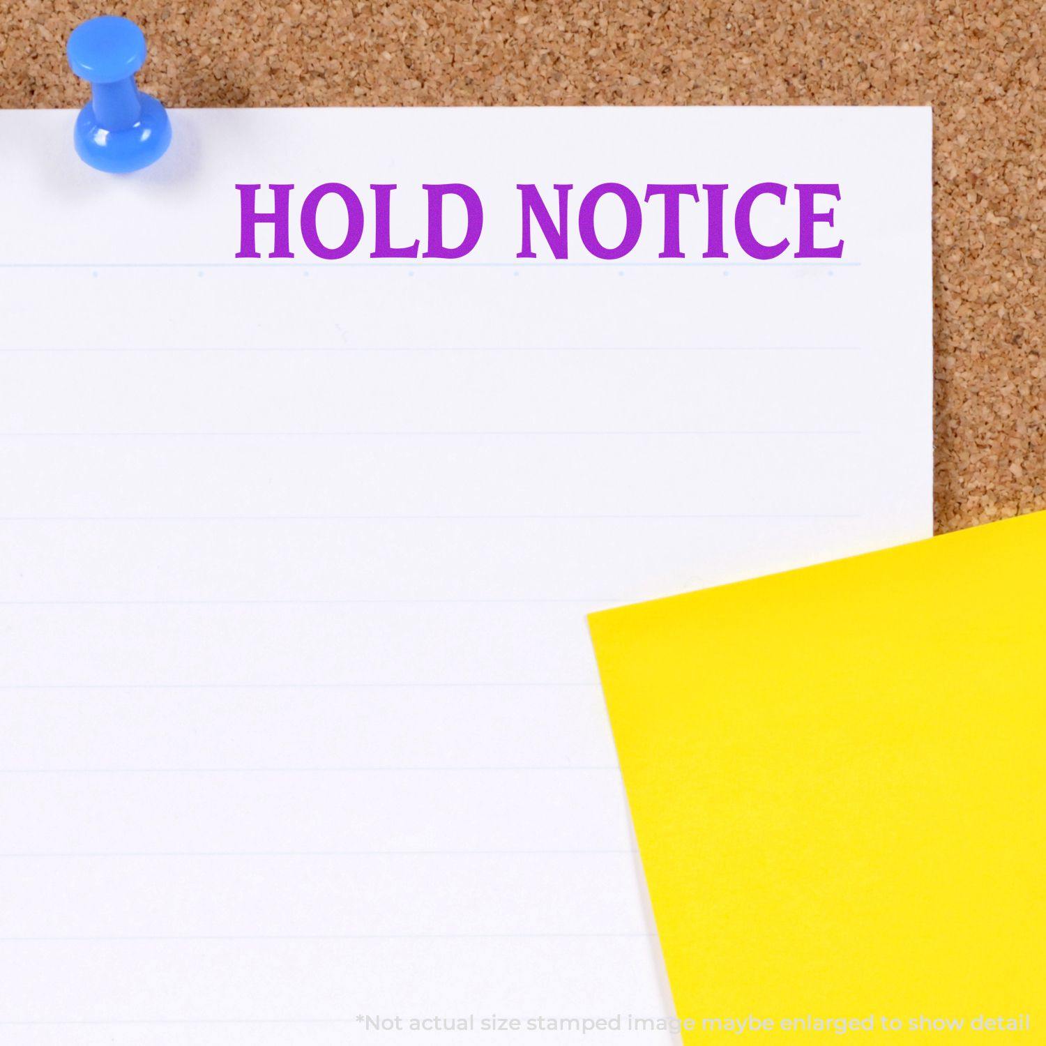 Large Hold Notice Rubber Stamp used on a white paper pinned to a corkboard with a blue pushpin, next to a yellow sticky note.