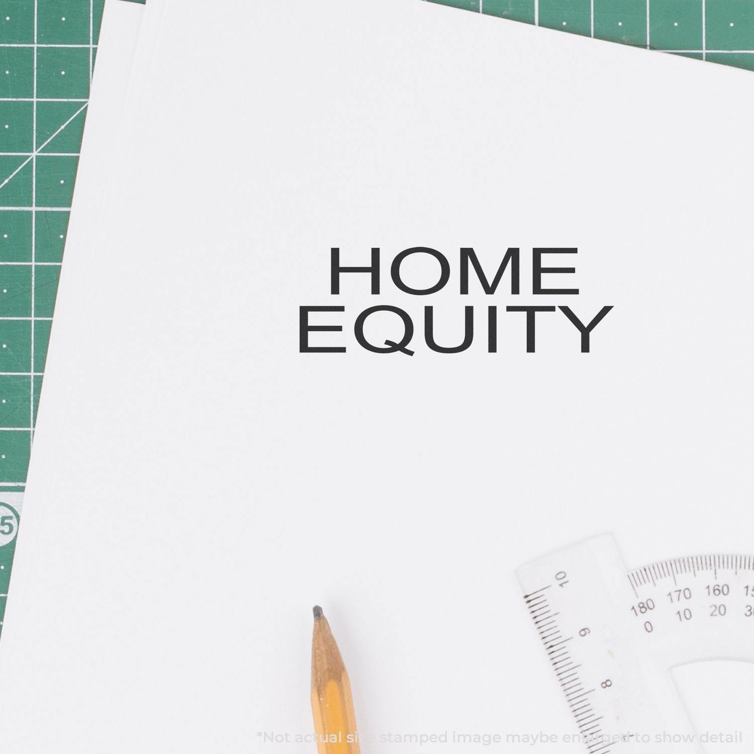 Self Inking Home Equity Stamp marking HOME EQUITY on a white paper, with a pencil and ruler nearby on a green cutting mat.