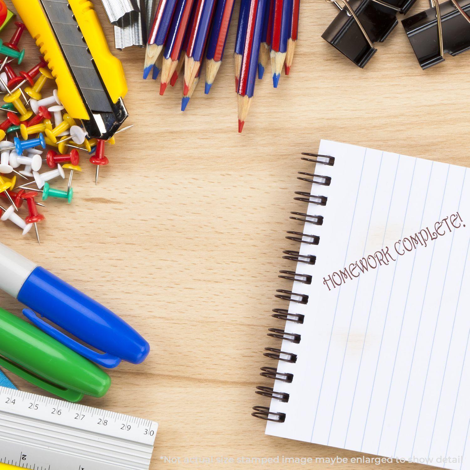 Desk with stationery items and a notebook stamped with Homework Complete! using the Self Inking Homework Complete Stamp.