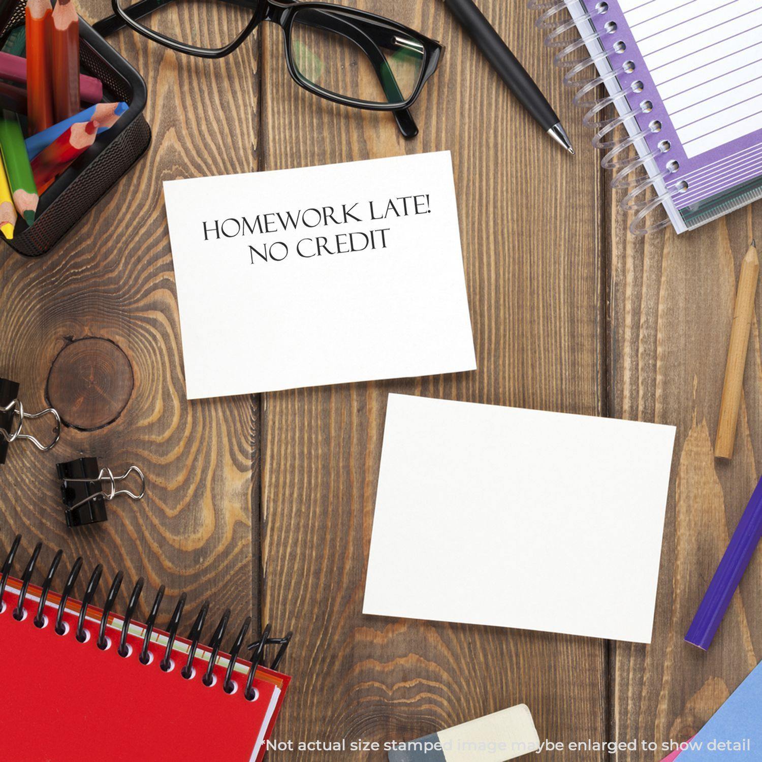 Desk with school supplies and a Large Homework Late No Credit Rubber Stamp on a card, indicating no credit for late homework.