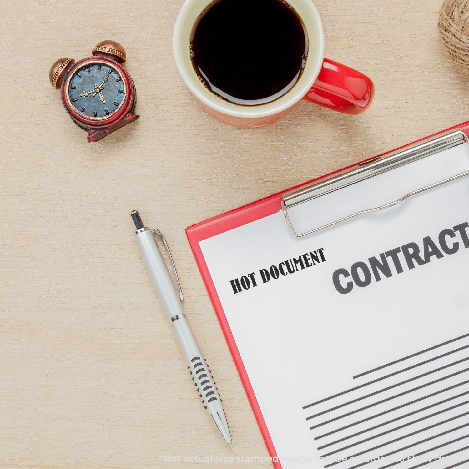 A desk with a clock, coffee, pen, and clipboard holding a contract stamped with HOT DOCUMENT using the Large Hot Document Rubber Stamp.