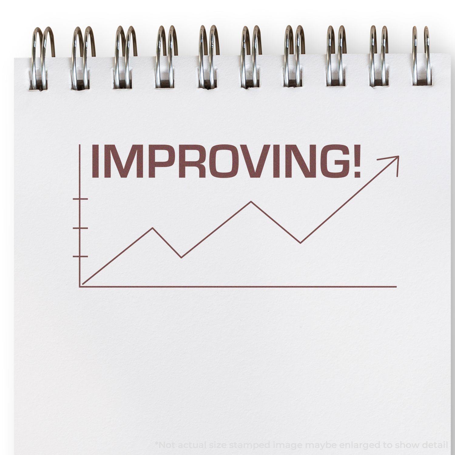 Improving with Chart Icon Rubber Stamp on a spiral notebook, showing a rising graph and the word IMPROVING! in bold letters.