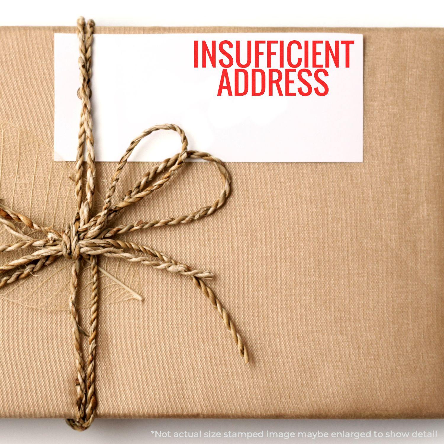 A brown package with a twine bow and a white card stamped with INSUFFICIENT ADDRESS in red using the Insufficient Address Rubber Stamp.