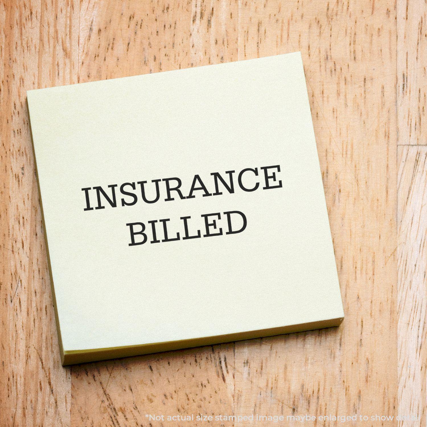 Large Insurance Billed Rubber Stamp on a yellow sticky note placed on a wooden surface.