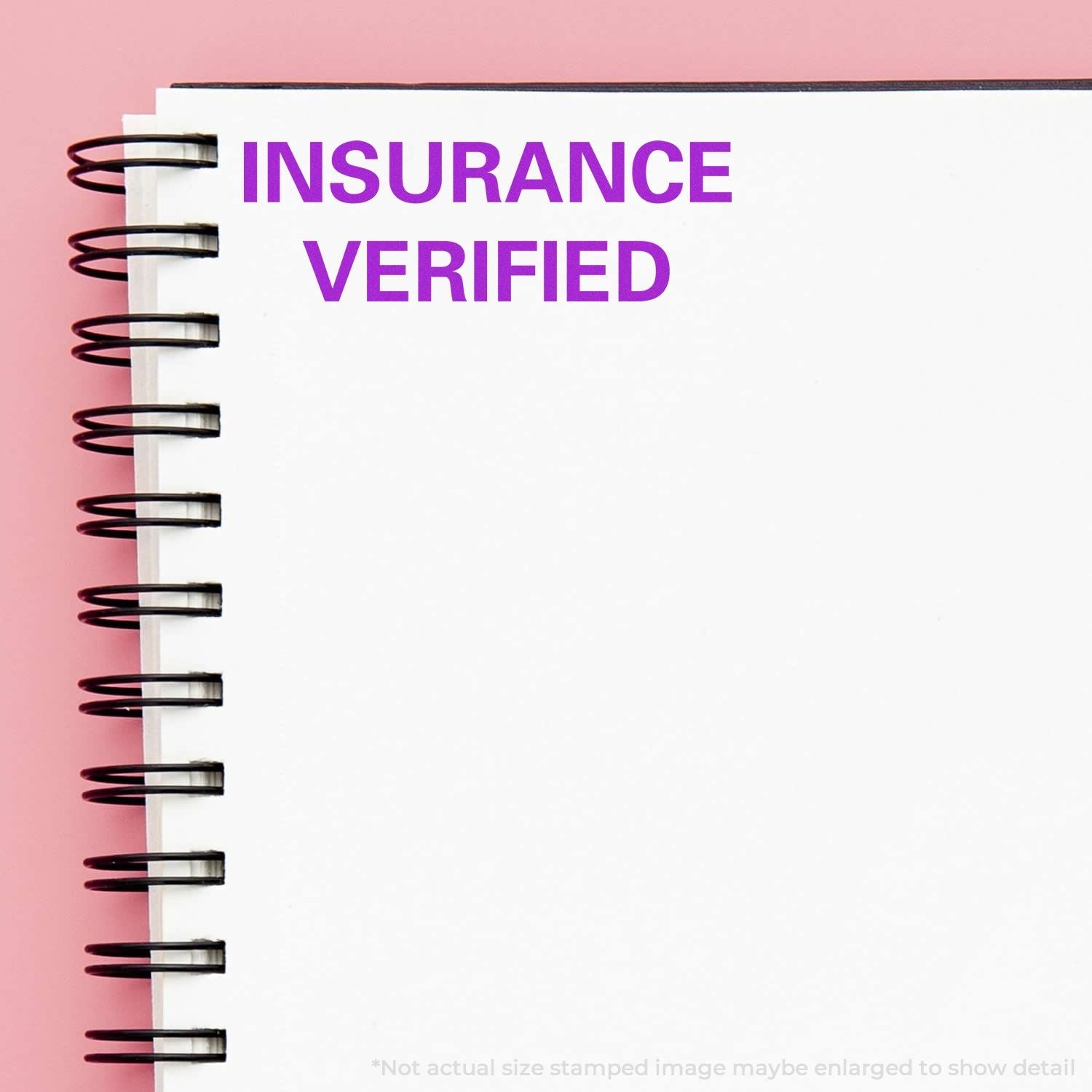 Self Inking Insurance Verified Stamp in purple ink on a white spiral notebook with a pink background.