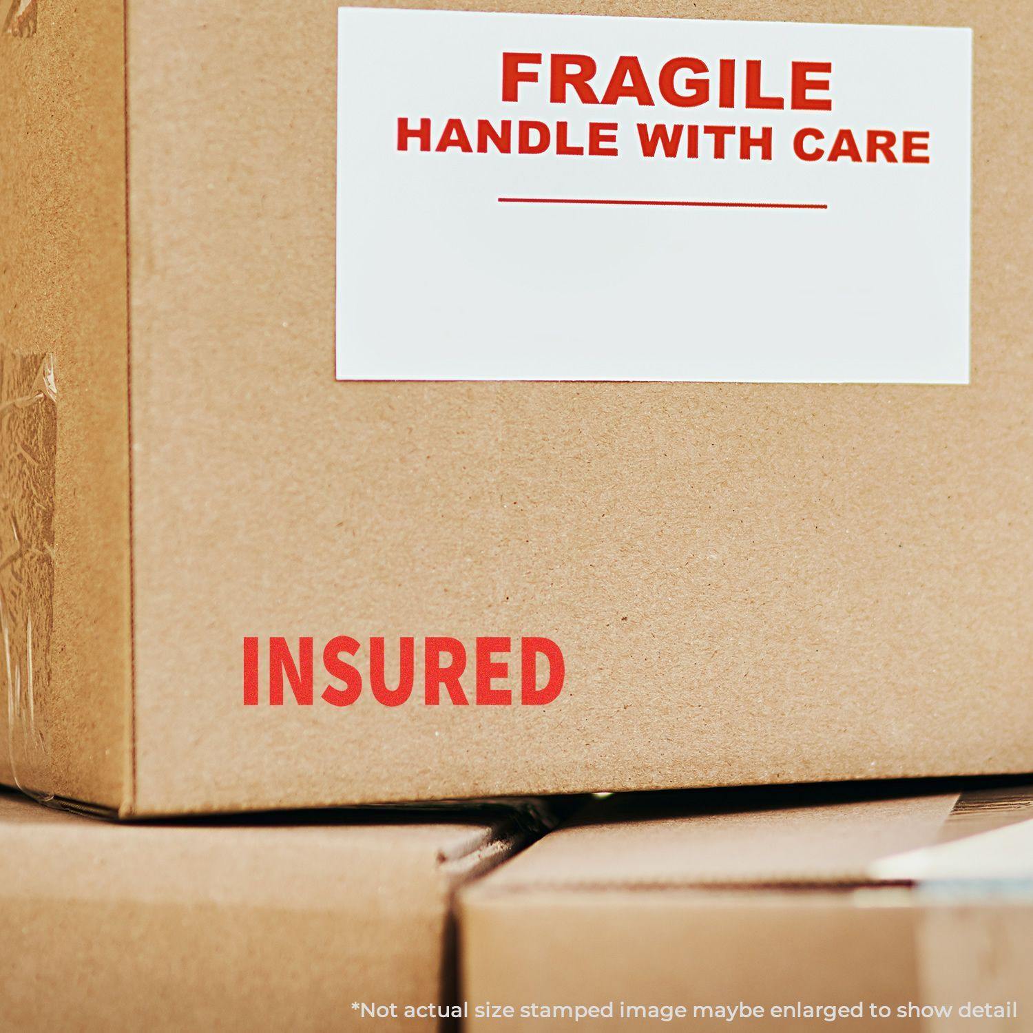 Cardboard box with FRAGILE HANDLE WITH CARE label and INSURED stamped in red using the Insured Rubber Stamp.