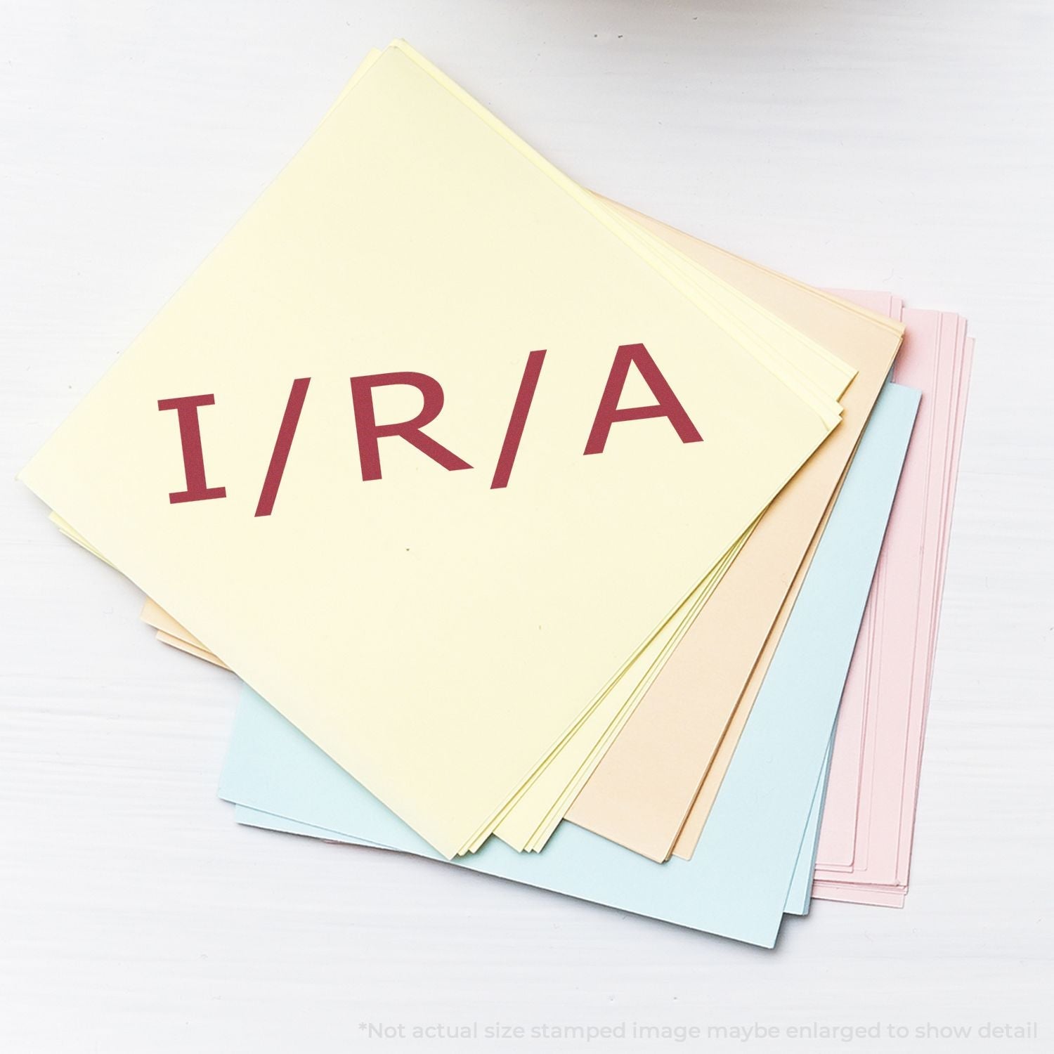 A stack of pastel-colored papers stamped with I/R/A using the Self Inking Ira Stamp.