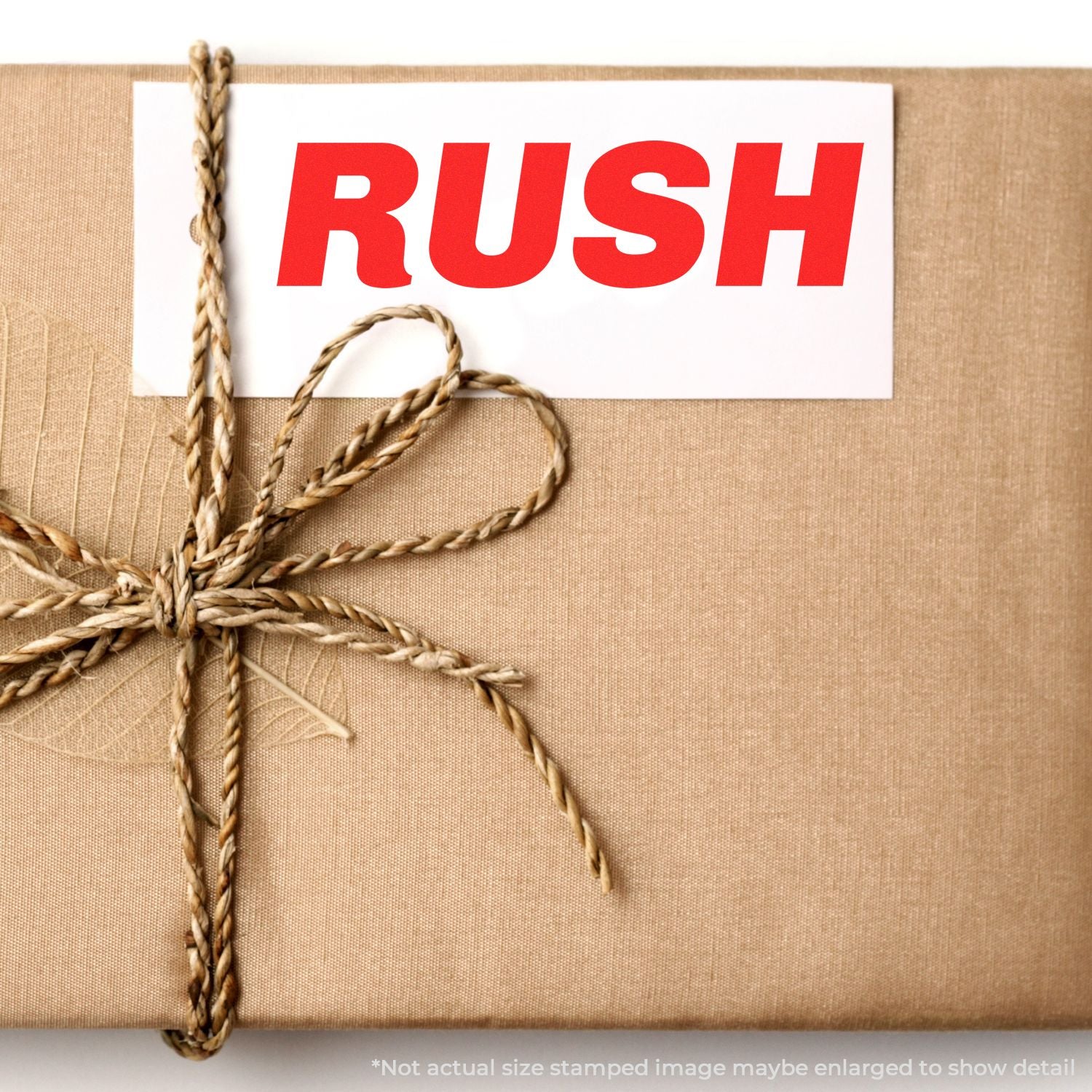 A brown package tied with twine, stamped with RUSH in red using the Self Inking Italic Rush Stamp.