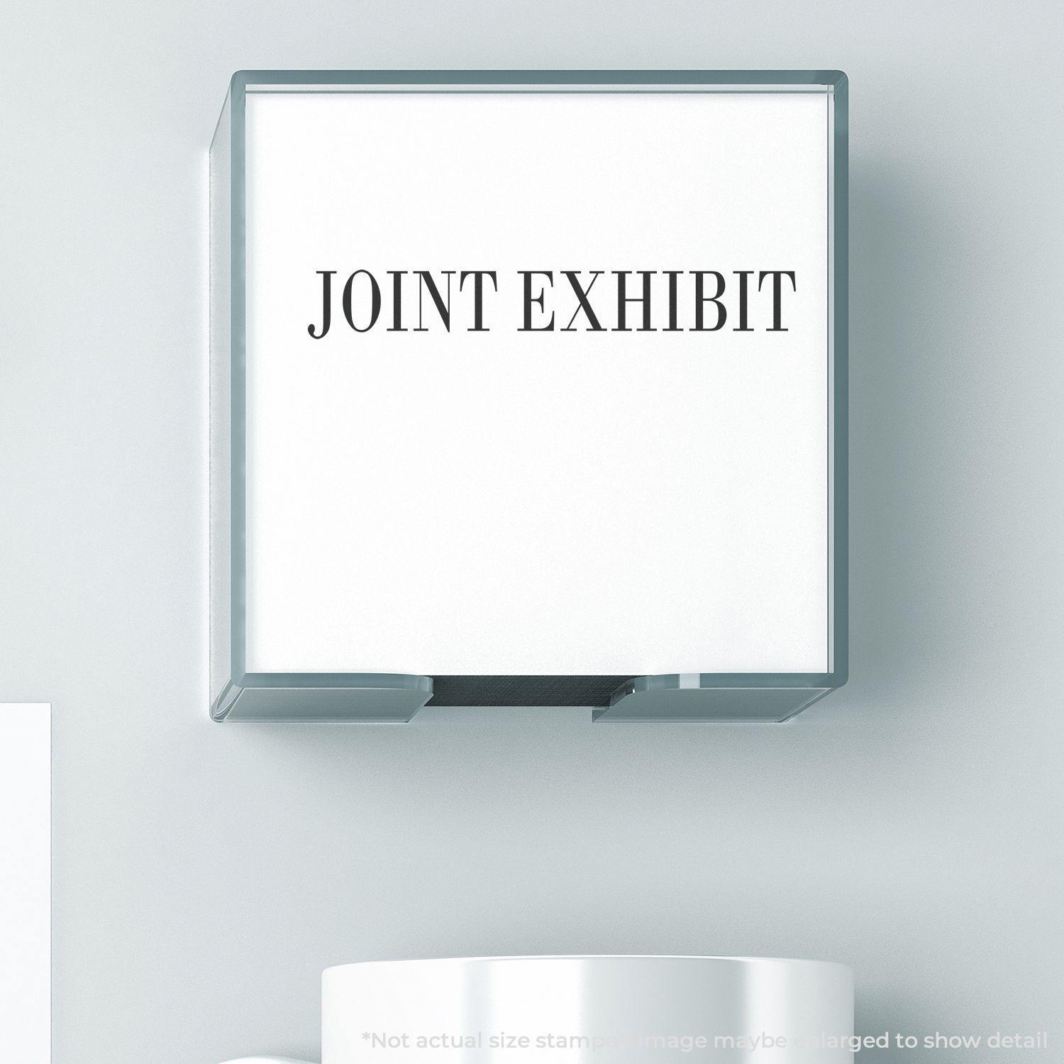 Slim Pre-Inked Joint Exhibit Stamp in use, displaying the text JOINT EXHIBIT on a white surface, close-up view.