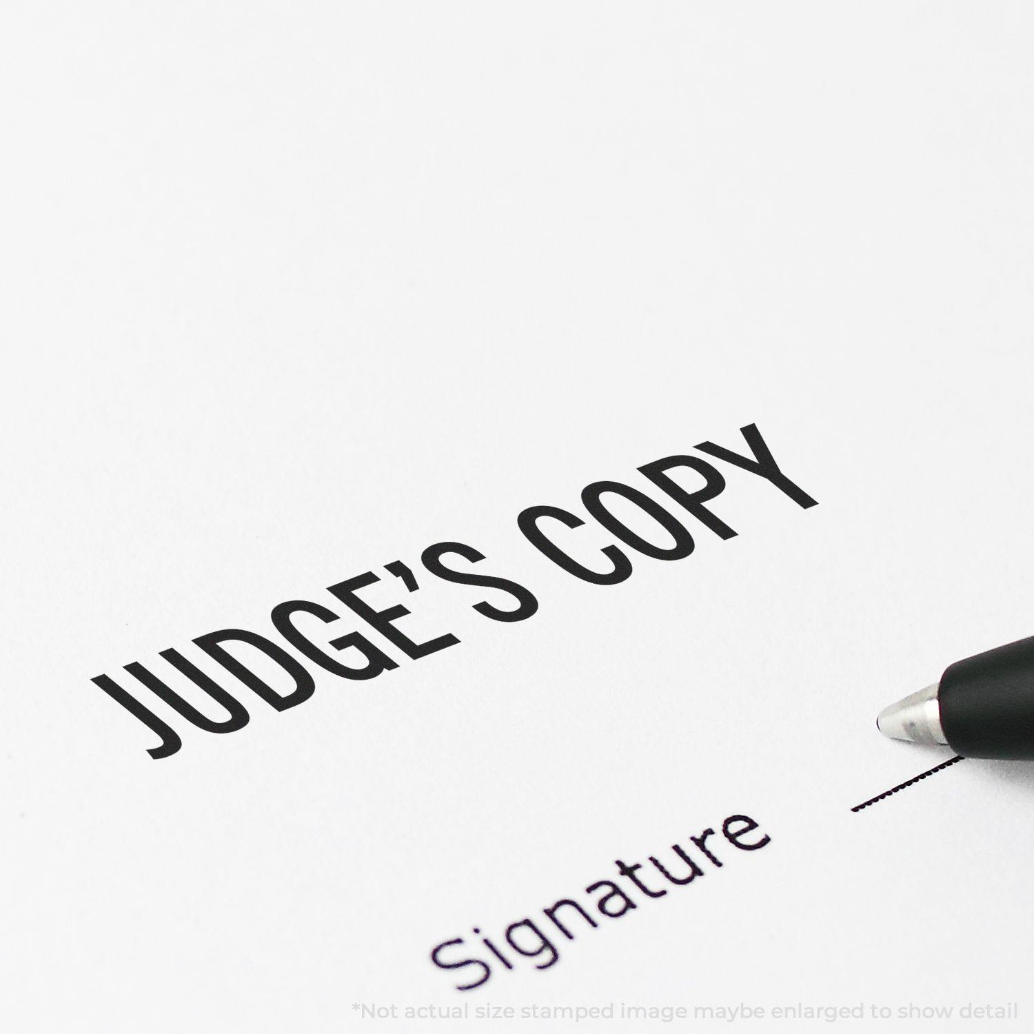 Large Self Inking Judge's Copy Stamp imprint on paper with a pen nearby. Text reads JUDGE'S COPY and Signature with a line for signing.