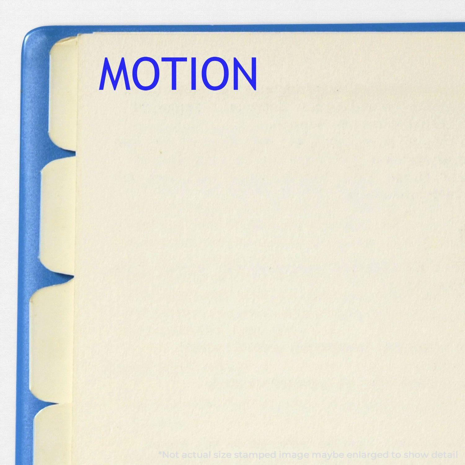 A stock office rubber stamp with a stamped image showing how the text "MOTION" in a large font is displayed after stamping.