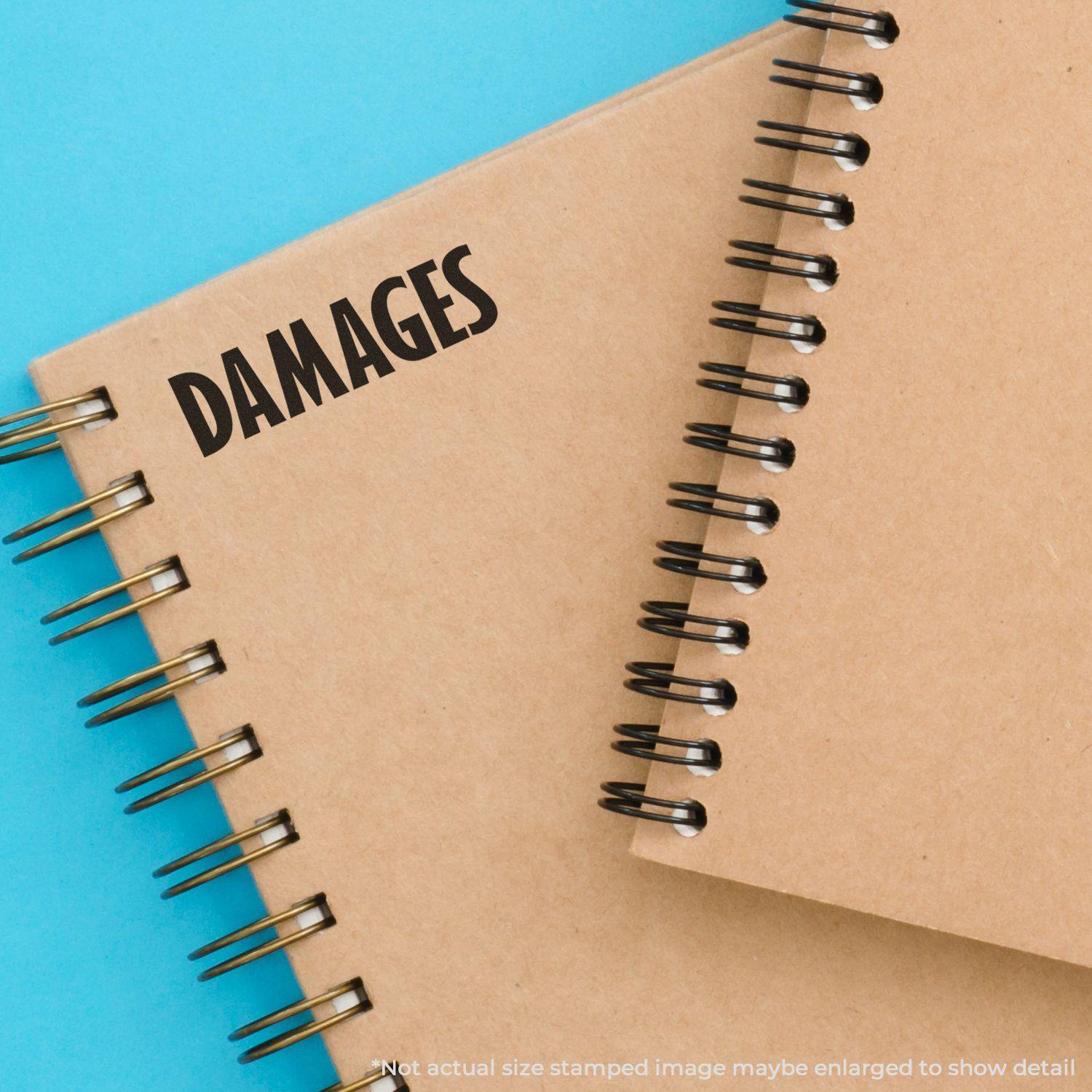 Notebook stamped with 'DAMAGES' using a Slim Pre-Inked Damages Stamp on a blue background. Text reads 'Not actual size stamped image.'