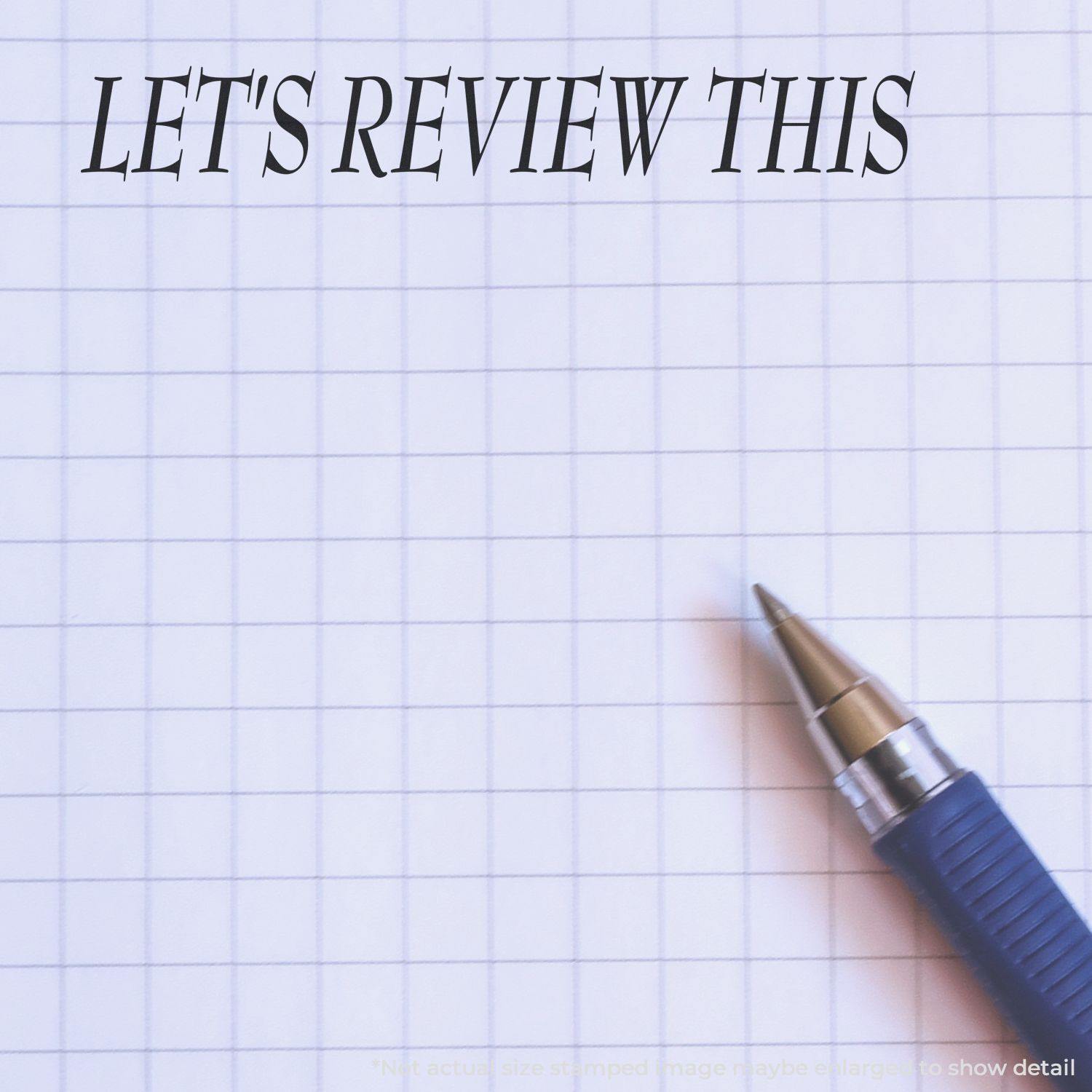 Large Lets Review This Rubber Stamp impression on graph paper with a blue pen beside it.