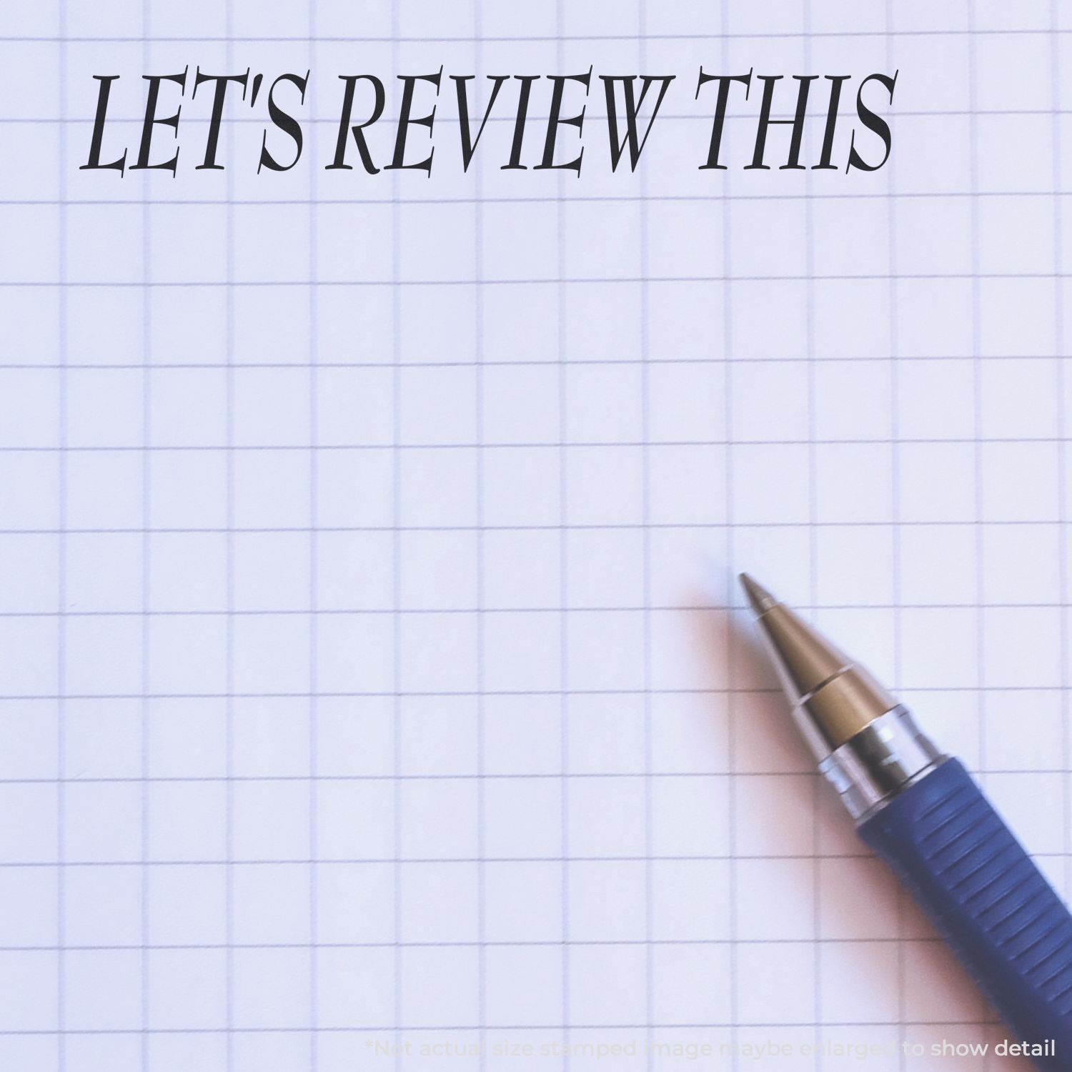 A blue pen next to a stamped message on graph paper reading LET'S REVIEW THIS using the Self Inking Let's Review This Stamp.